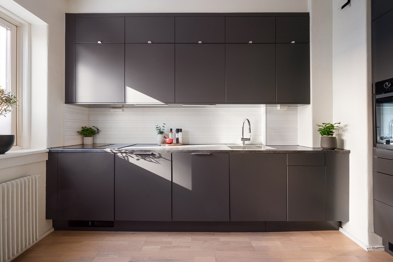 Kjøkkeninnredningen er moderne med glatte, grå fronter. Galleribilde