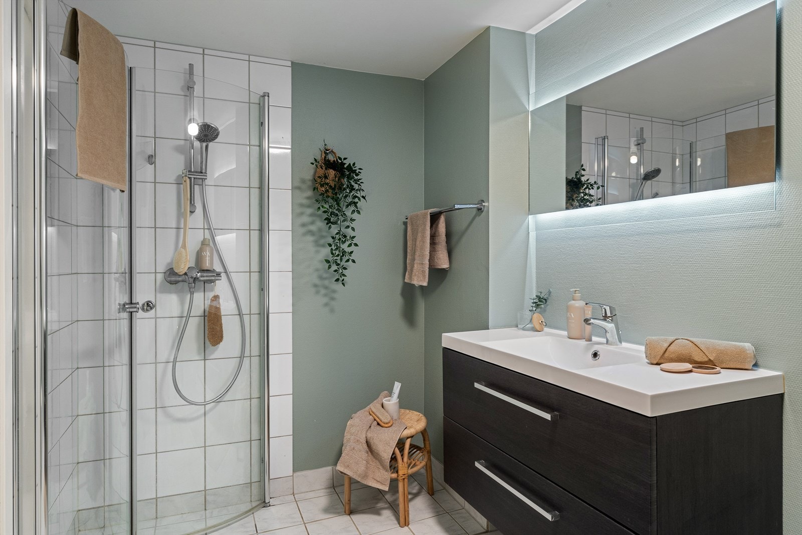 Badet er utstyrt med baderomsinnredning med servant, speil med belysning og dusjhjørne. Galleribilde