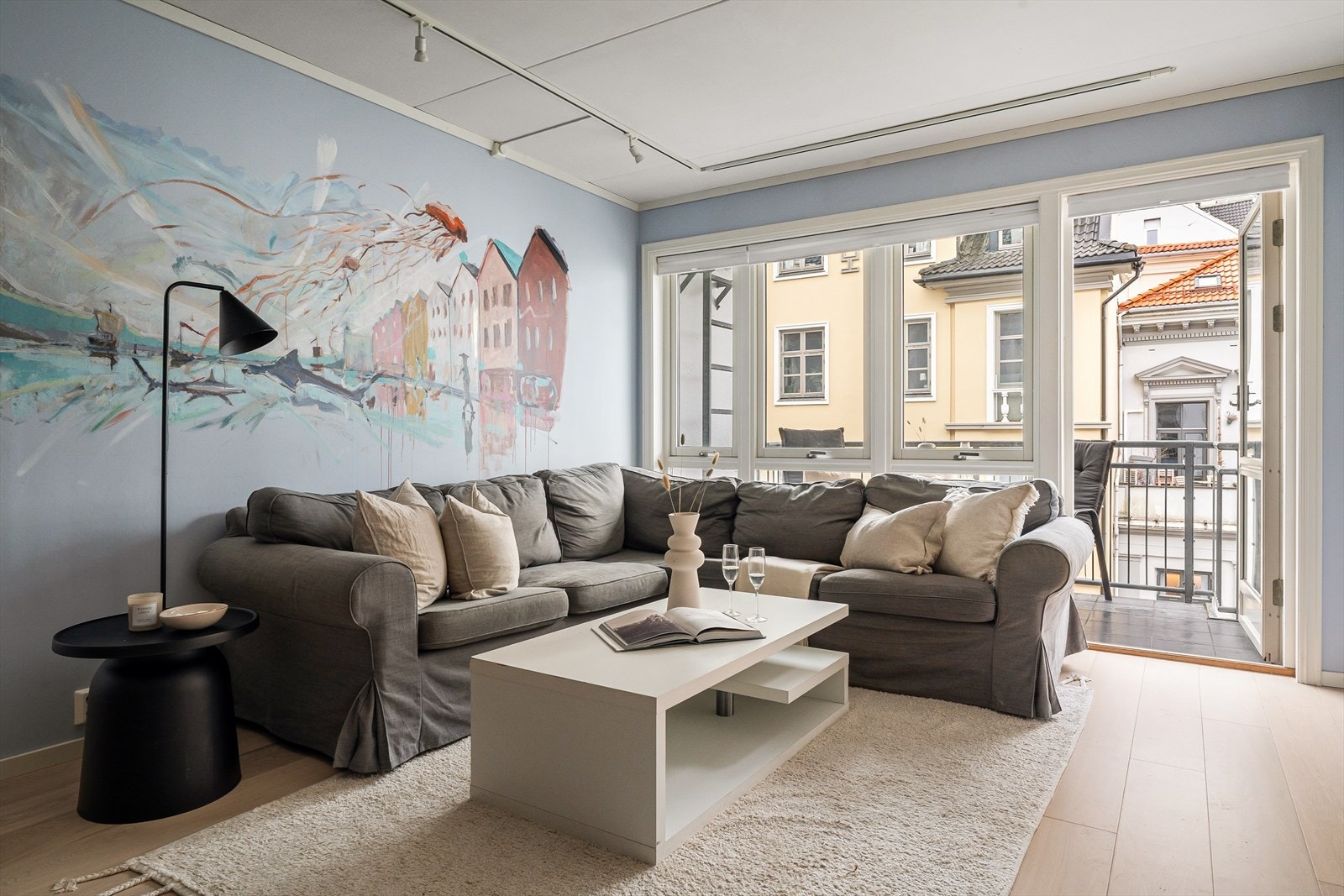 Lys og åpen stue med parkett på gulv og store vindusflater Galleribilde