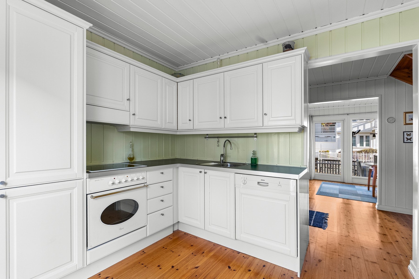 Kjøkkenet har hvite fronter, god skapplass og integrerte hvitevarer. Lys og romslig atmosfære med naturlig lysinnslipp. Galleribilde