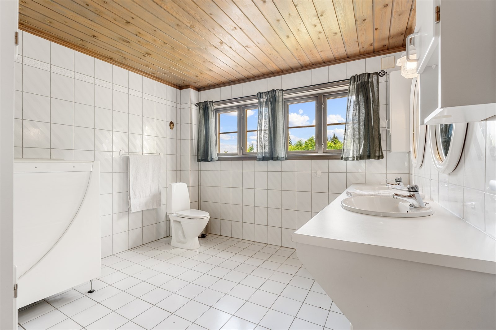 Badet i 1. etasje er romslig og lyst med flislagte overflater, gulvvarme, dobbel servant, toalett og badekar tilrettelagt for handikappede fjernes før overtakelse Galleribilde