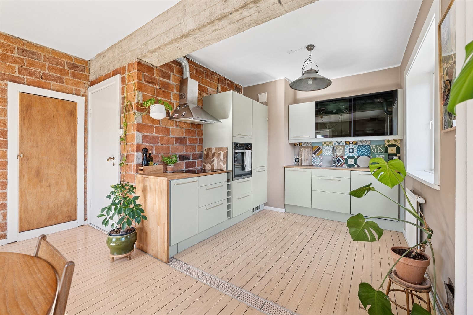 Moderne og stilrent kjøkken med glatte, malte fronter og integrerte hvitevarer. Den åpne løsningen gir god plass til spisebord og skaper en lys og luftig atmosfære. Galleribilde