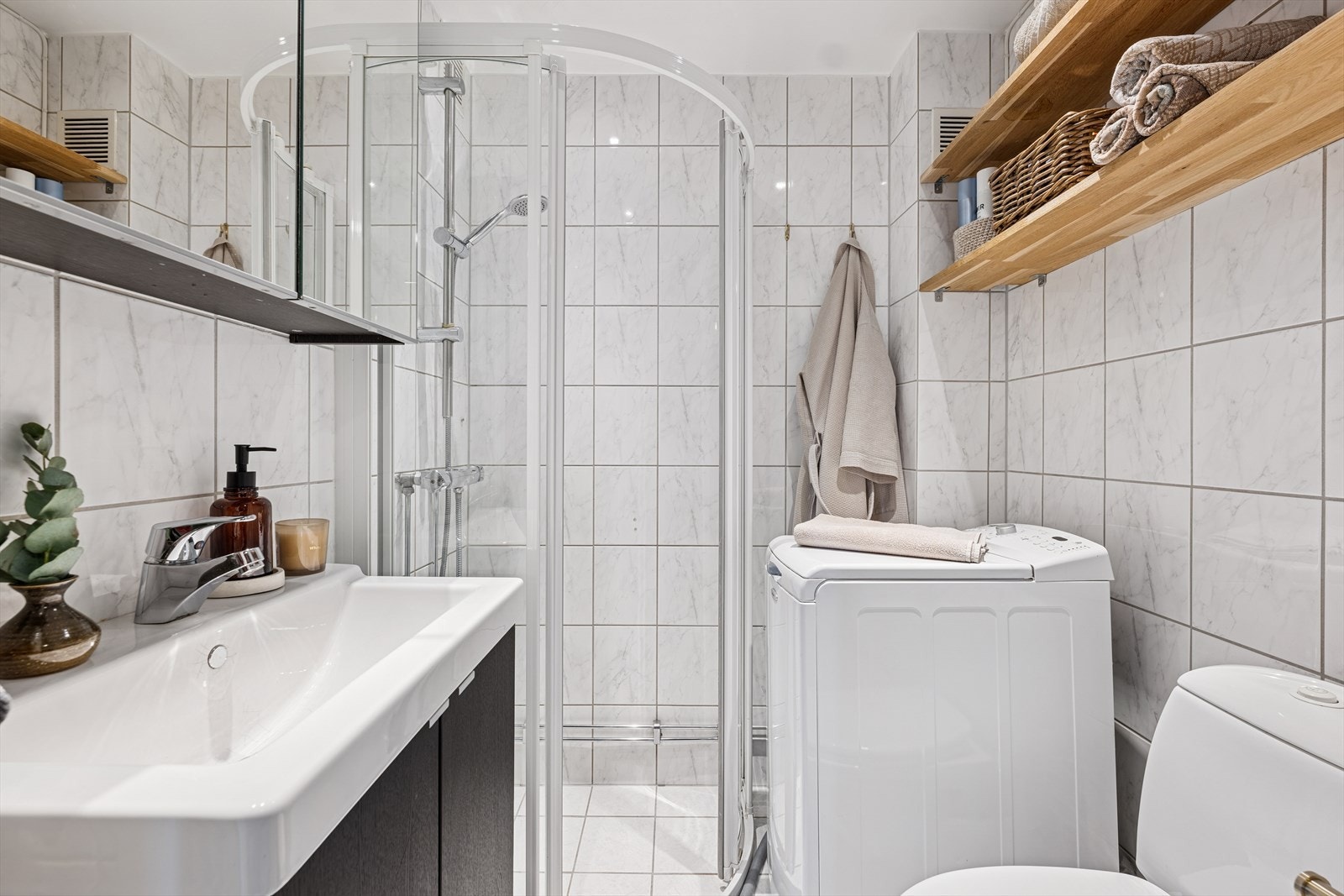 Effektivt utnyttet bad med vaskemaskin, dusjkabinett og gode oppbevaringsmuligheter. Galleribilde