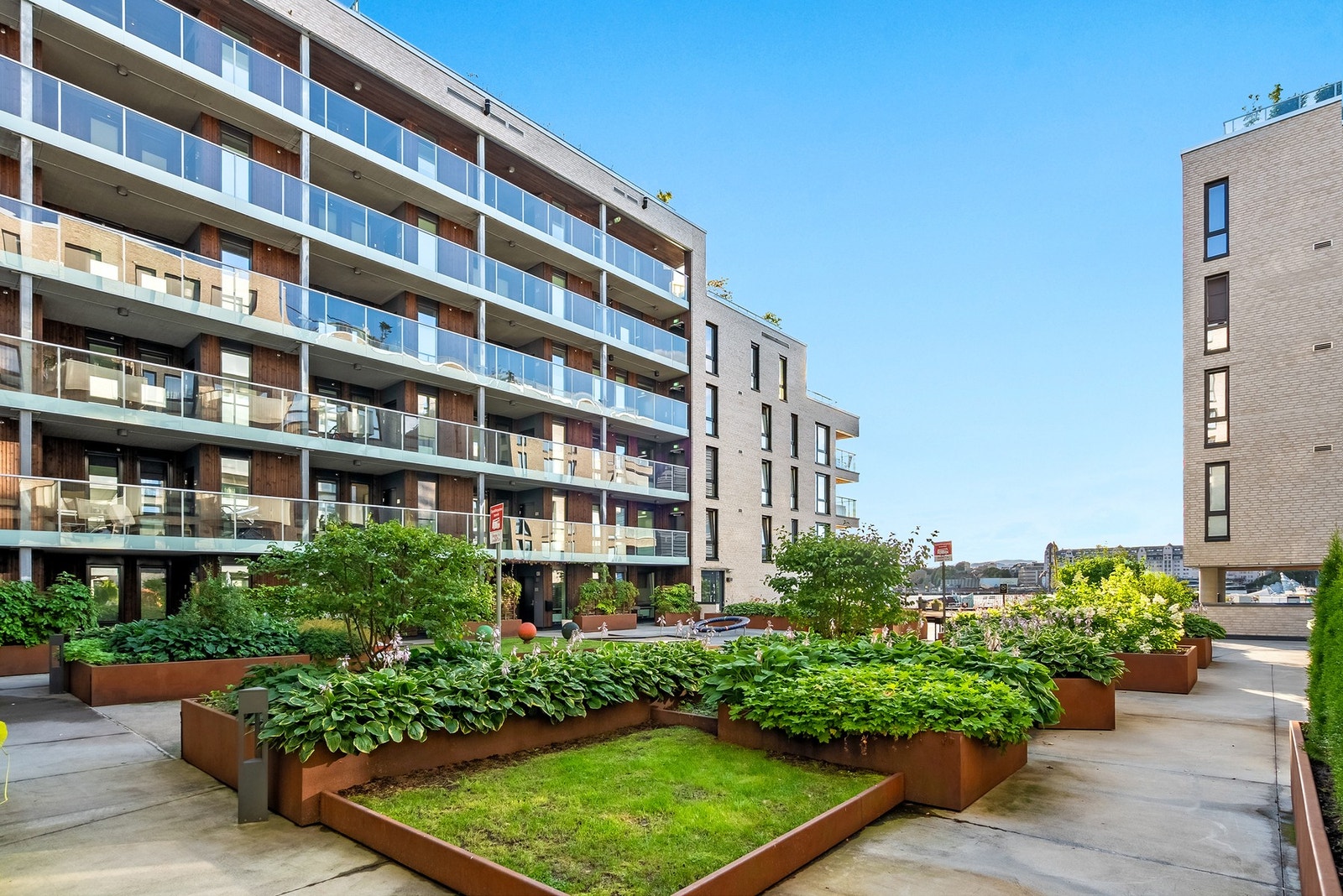 Det hyggelige gårdsrommet er pent opparbeidet med bl.a. steinsatte arealer, blomsterbed, variert beplantning, lekeapparater og sittegrupper. Galleribilde