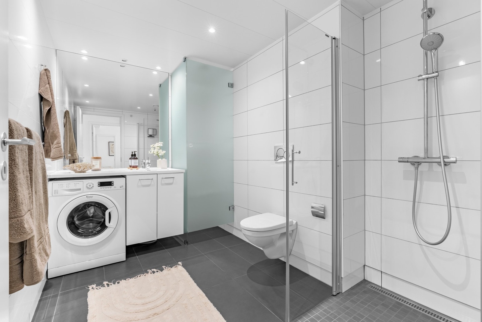 Baderommet har også god størrelse. Her er det varmekabler i gulv og dimbare downlights i himling. Praktisk tørkeskap i enden av innredningen. Galleribilde