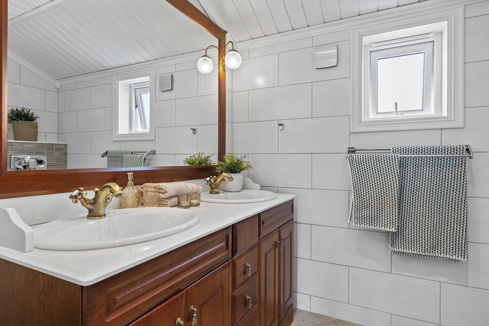 Helfliset baderom med varmekabler i gulv. Badet er utstyrt med dobbel servant over skapinnredning, speil, vegghengt toalett og dusjkabinett. Galleribilde