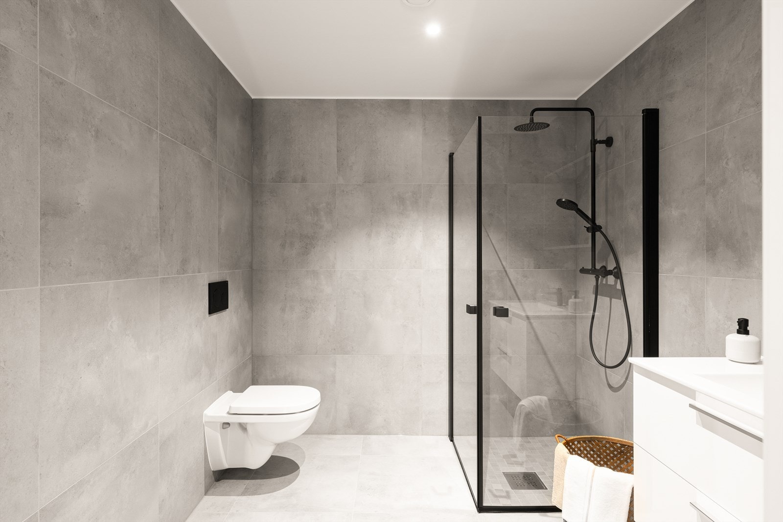 Lekkert Bad/wc med flislagte vegger og flislagt gulv med vannbåren gulvvarme. Malt gipstak med innfelte LED downlights med dimmer. Veggmontert wc. Dusjhjørne med 90x90 cm glassvegger. Hvit slett baderomsinnredning med LED speil Galleribilde