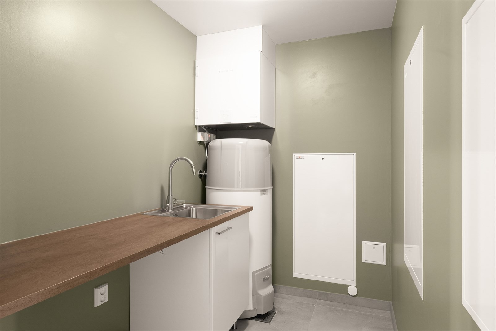 Vaskerom/teknisk rom har fliser på gulv med vannbåren gulvvarme og malte gipsvegger. Malt gipstak. varmtvannsbereder fra Høyax og balansert ventilasjon med varmegjenvinning fra Systemair. Vaskeromsinnredning med utslagsvask, benkeplate og skap Galleribilde