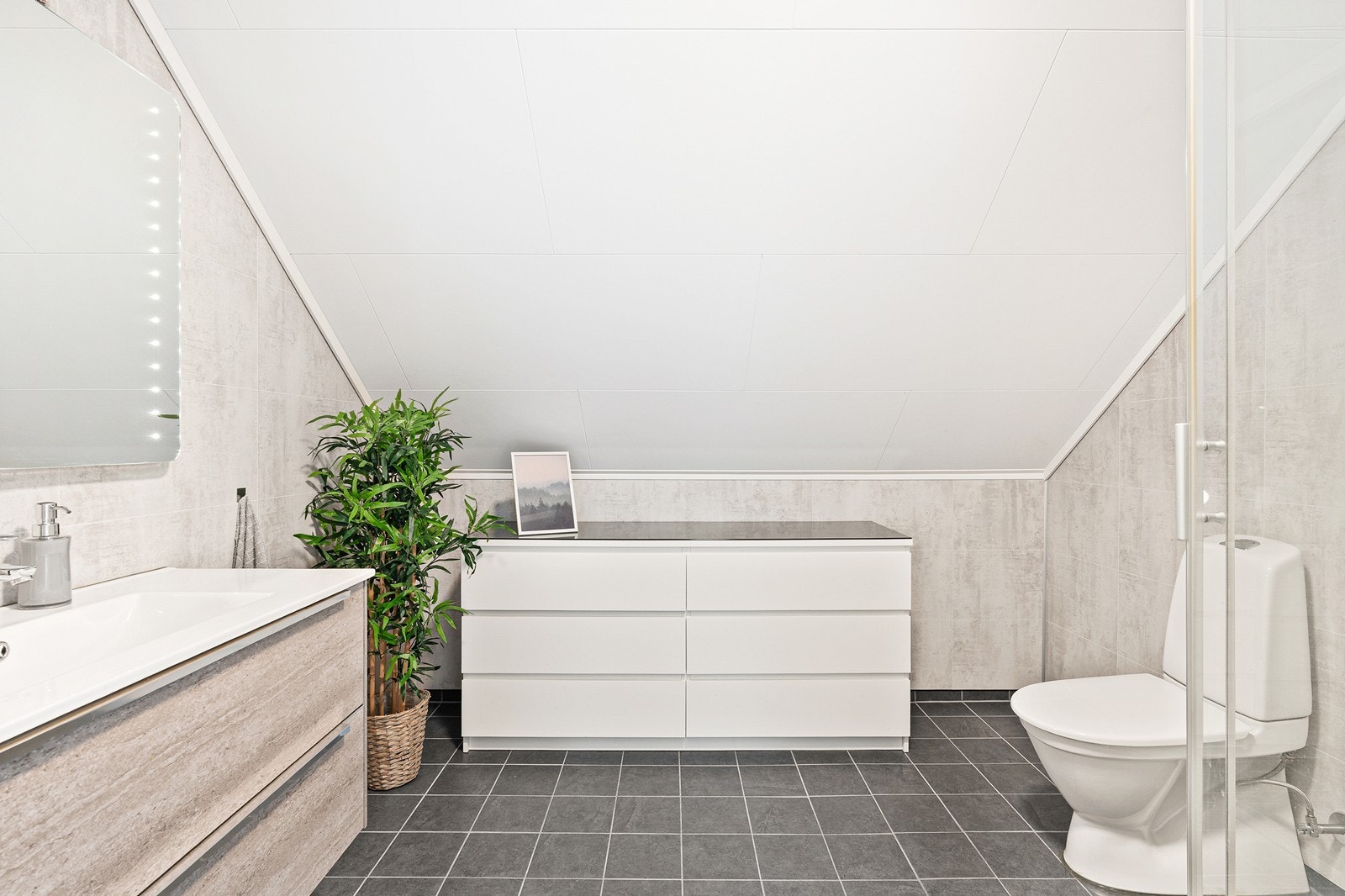 Bad på loft har gulvfliser med varmekabler, panelplater på vegg og himlingsplater i tak. Galleribilde