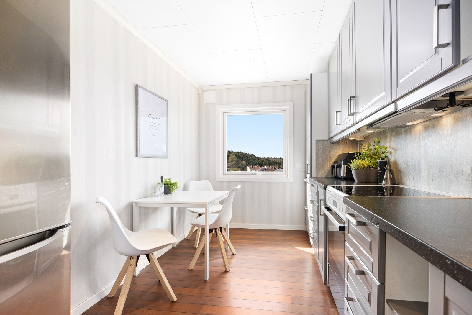 Kjøkkenet har en stilren innredning med profilerte fronter og en praktisk benkeplate i laminat. Nedfelt stålvask med ettgreps blandebatteri gir både funksjonalitet og et moderne uttrykk. Galleribilde