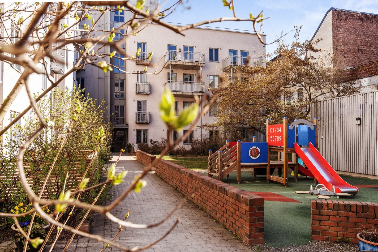 I bakgården er det formiddagssol. Her er det opparbeidet med prydbusker og lekeplass. Galleribilde