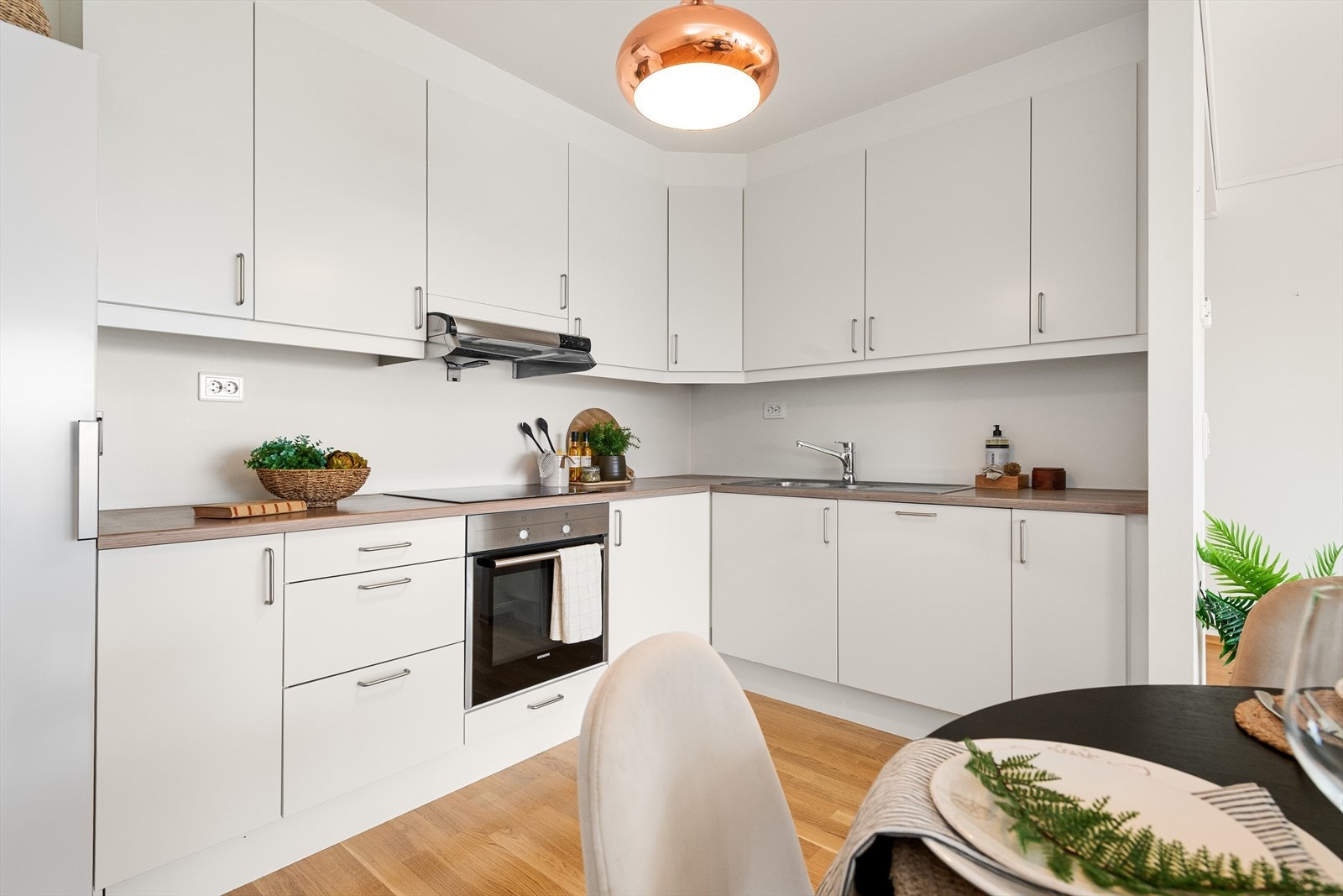 Kjøkkenet har innredning med hvite, glatte fronter, kjøleskap, oppvaskmaskin, induksjonstopp og stekeovn. Galleribilde