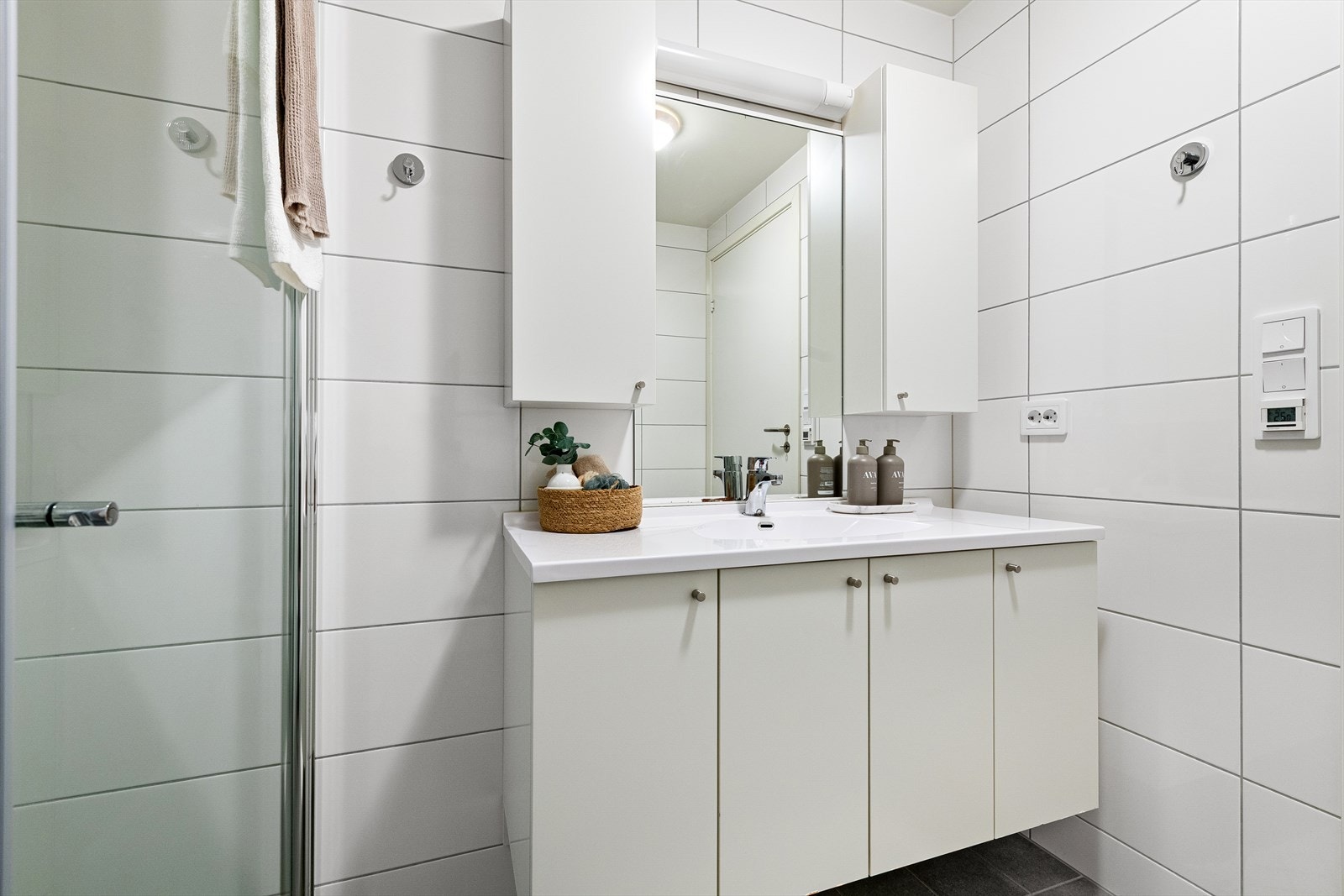 Badet er innredet med servant, veggtoalett og dusjhjørne med glassdører. Galleribilde