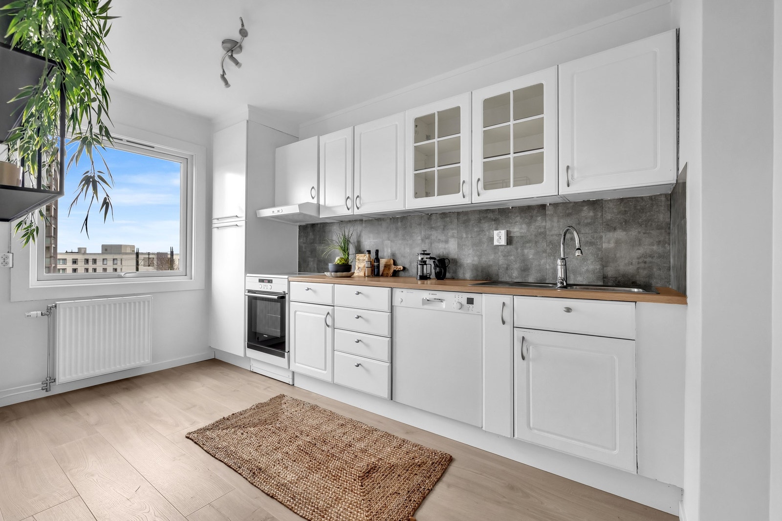 Lyst kjøkken med godt med skap og benkeplass. Kjøkkenet er av god størrelse og gir muligheten til å sette opp et lite kjøkkenbord for dagens mindre måltider. Galleribilde