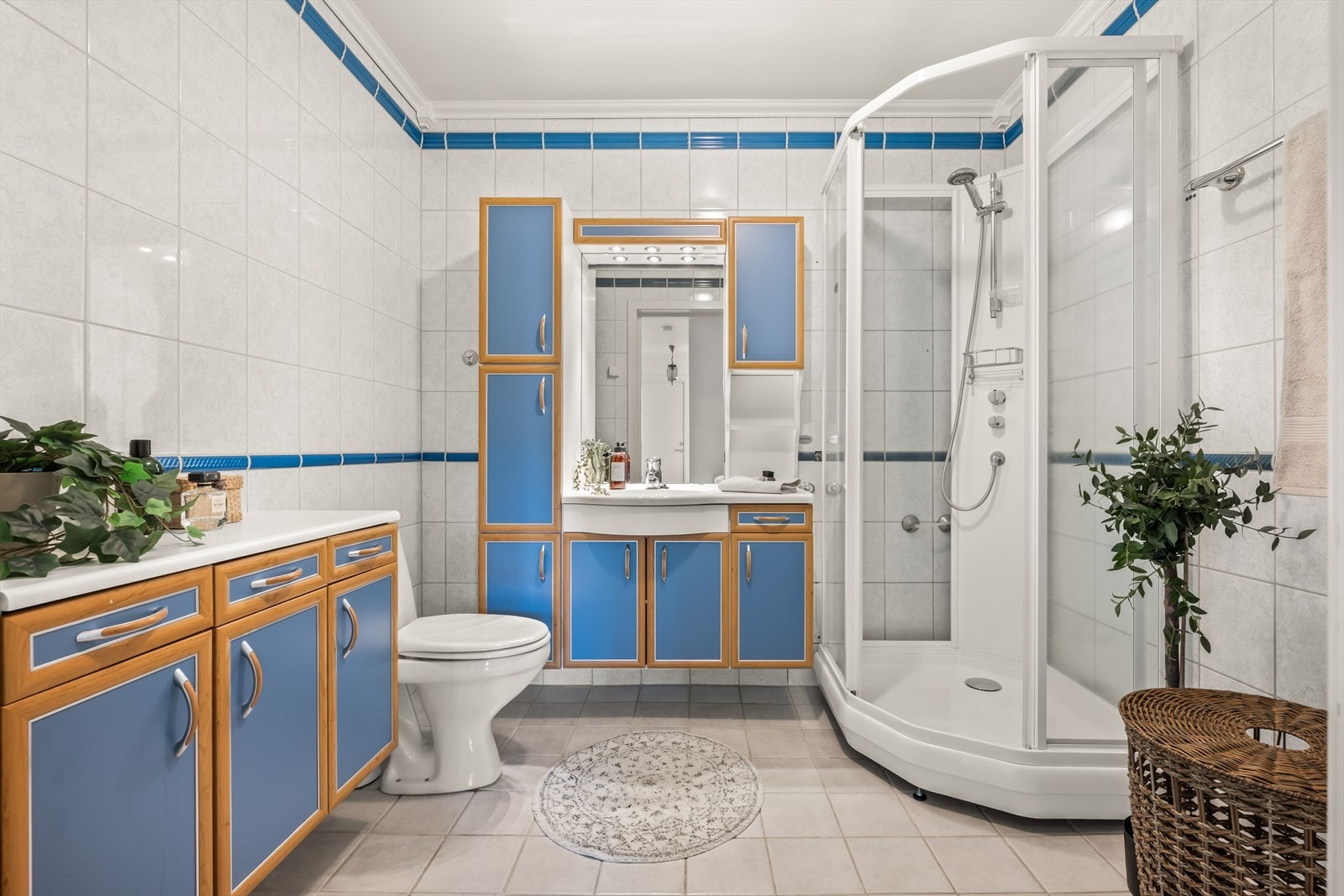Romslig flislagt bad med varmekabler i gulv. Badet er innredet med heldekkende servant med skapinnredning og belysning, toalett og dusjkabinett i hjørne. Rommet har opplegg for vaskemaskin Galleribilde