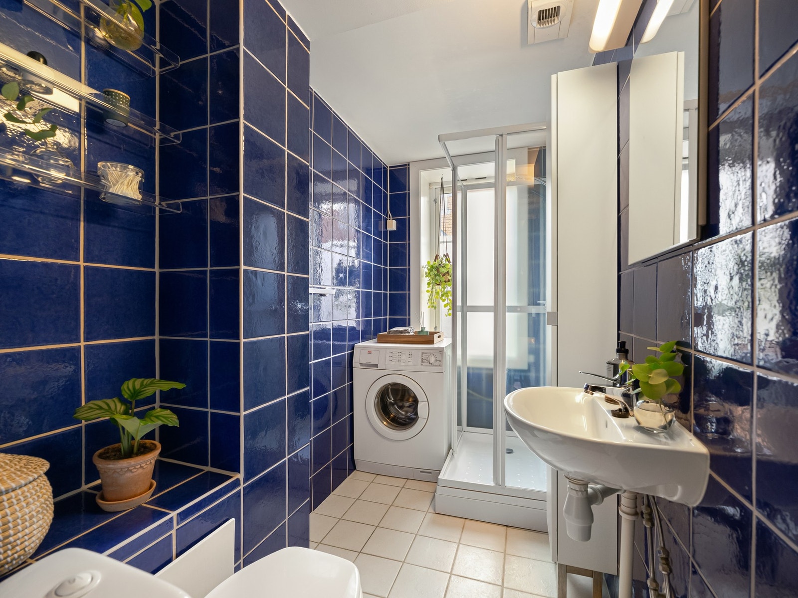 Badet er innredet med dusjkabinett, servant, høyskap og speil. Det er plass og opplegg for vaskemaskin og varme i gulvet. Galleribilde