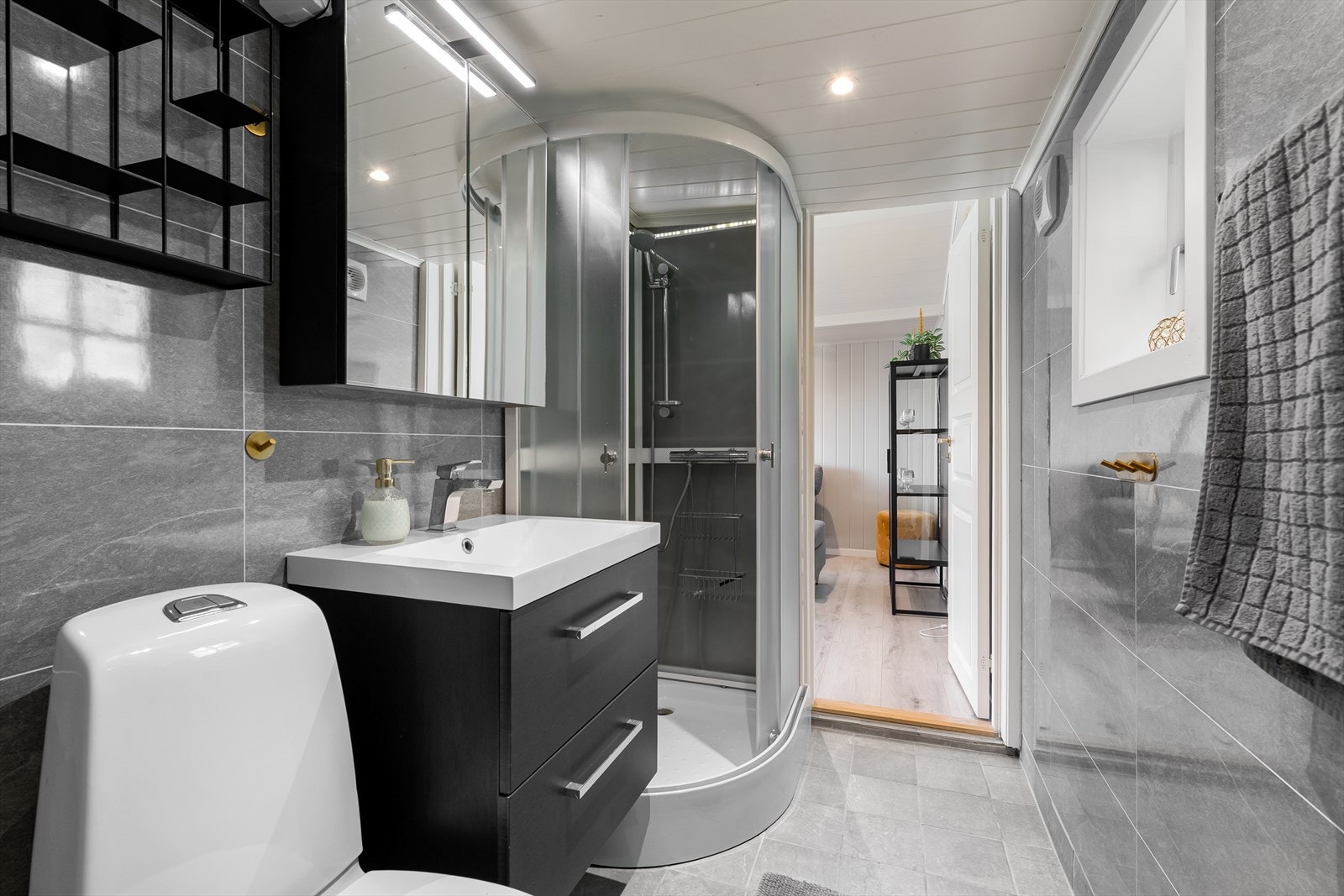 Badet er innredet med vegghengt toalett, dusjkabinett og innredning med servant. Galleribilde