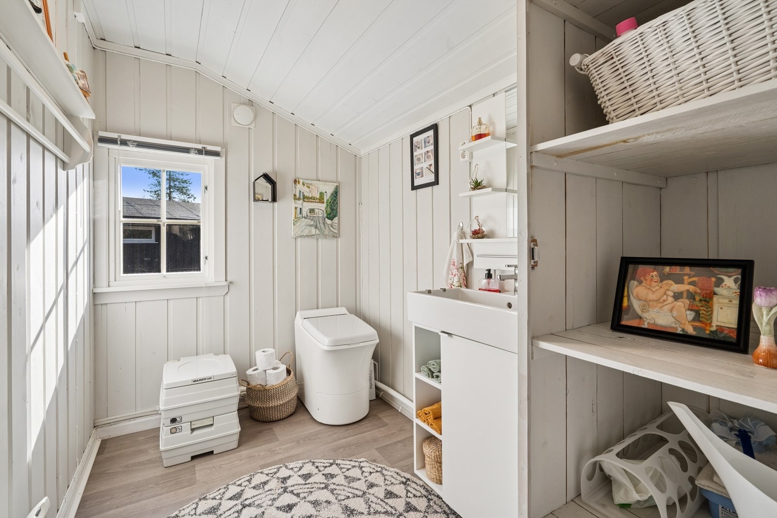 Toalettommet inneholder servantskap med heldekkende servant, cinderella forbrenningstoalett og visa porty toalett. Galleribilde