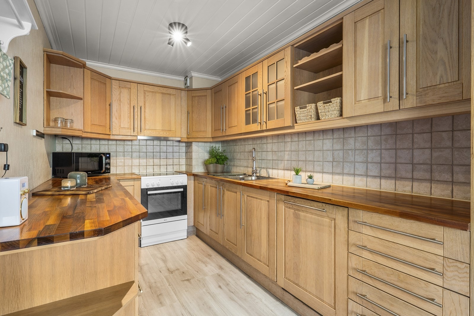 Flis på vegg mellom overskap og benk. Integrert oppvaskmaskin og kjøleskap som medfølger i salget. Det er montert lekkasjestopper. Kjøkkenvifte med kullfilter, samt elektriske vifte Galleribilde