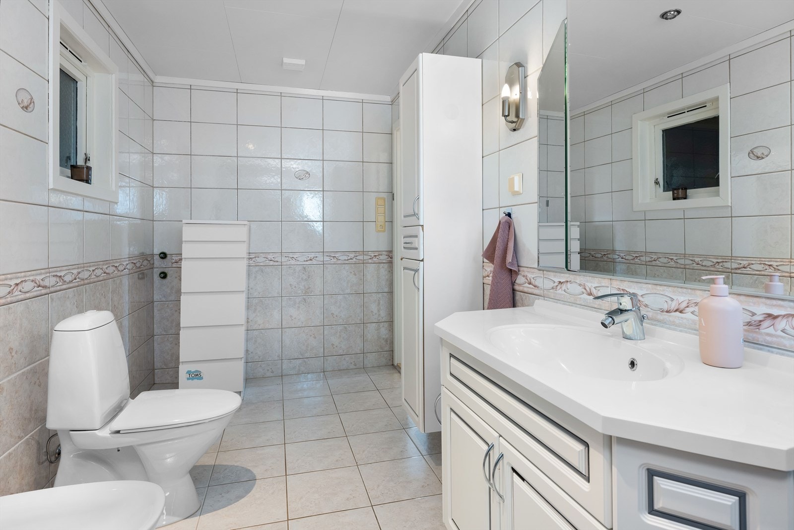 Badet er helfliset og har innredning som wc, servantinnredning med skap og dusjkabinett. Galleribilde