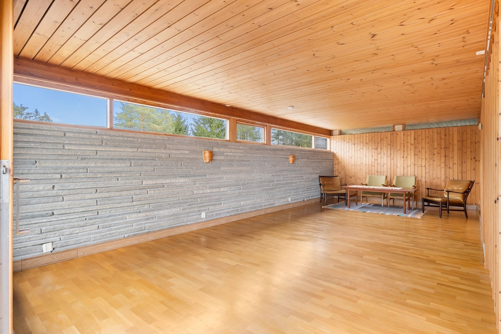 Et hovedgrep fra arkitekten er at den lange skifermuren går sømløst fra stuevegg og ut i friluft og avskjermer terrassen ute mot nord. Galleribilde