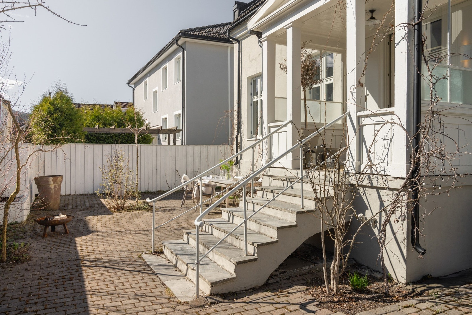 Boligens hovedinngang med adkomst via skiferbelagt trapp til veranda med overbygg hvilende på søyler. Galleribilde