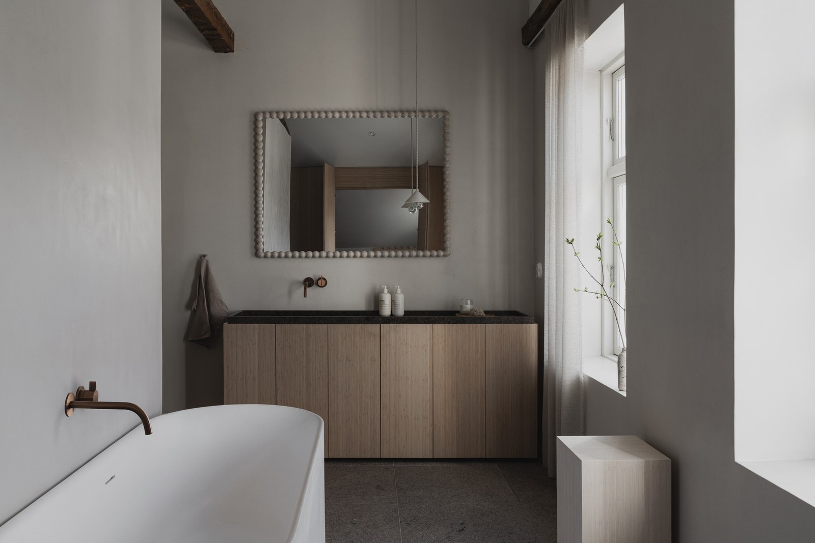 Badet er elegant og stilrent designet med badekar i midtre sone, veggmontert toalett innerst og dusjnisje i ytre del. Galleribilde