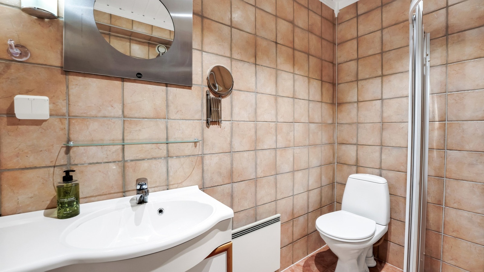 Flislagt bad med nedfelt servant, toalett og dusjvegger/hjørne. Galleribilde