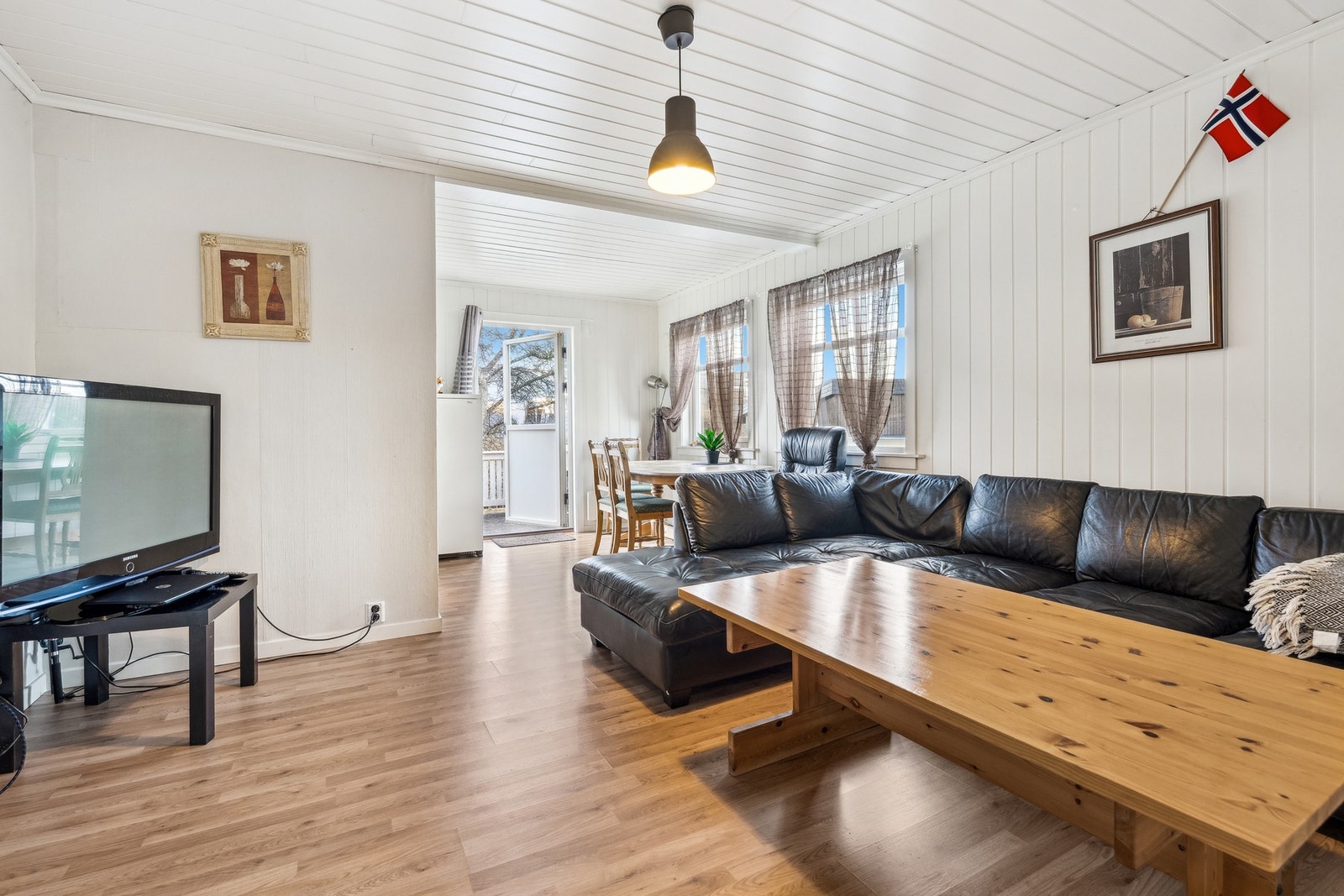 Stor og åpen stue med delvis åpen løsning mot kjøkkenet ved spisebordet. Galleribilde