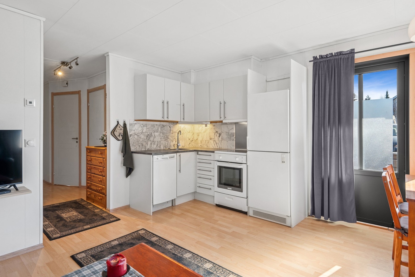 Naturlig lys fra vinduene i stuen bidrar til en lysere kjøkkenopplevelse. Galleribilde