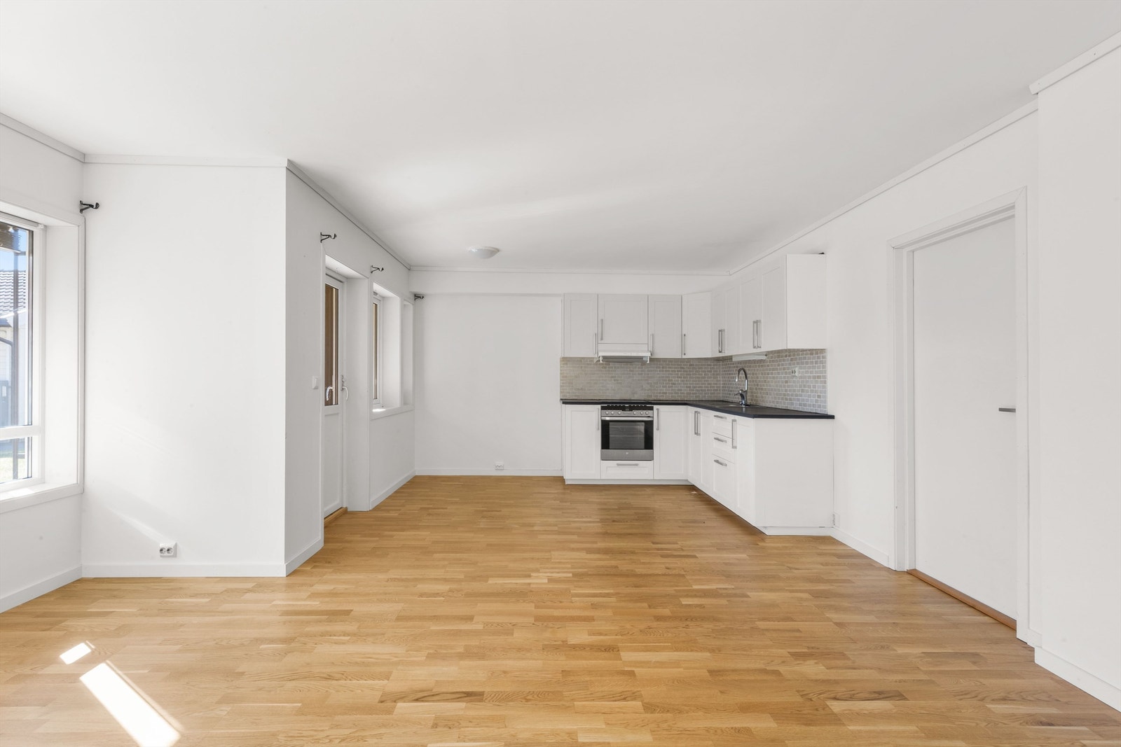 Den åpne løsningen mellom stue og kjøkken gir leiligheten en luftig og romslig følelse Galleribilde