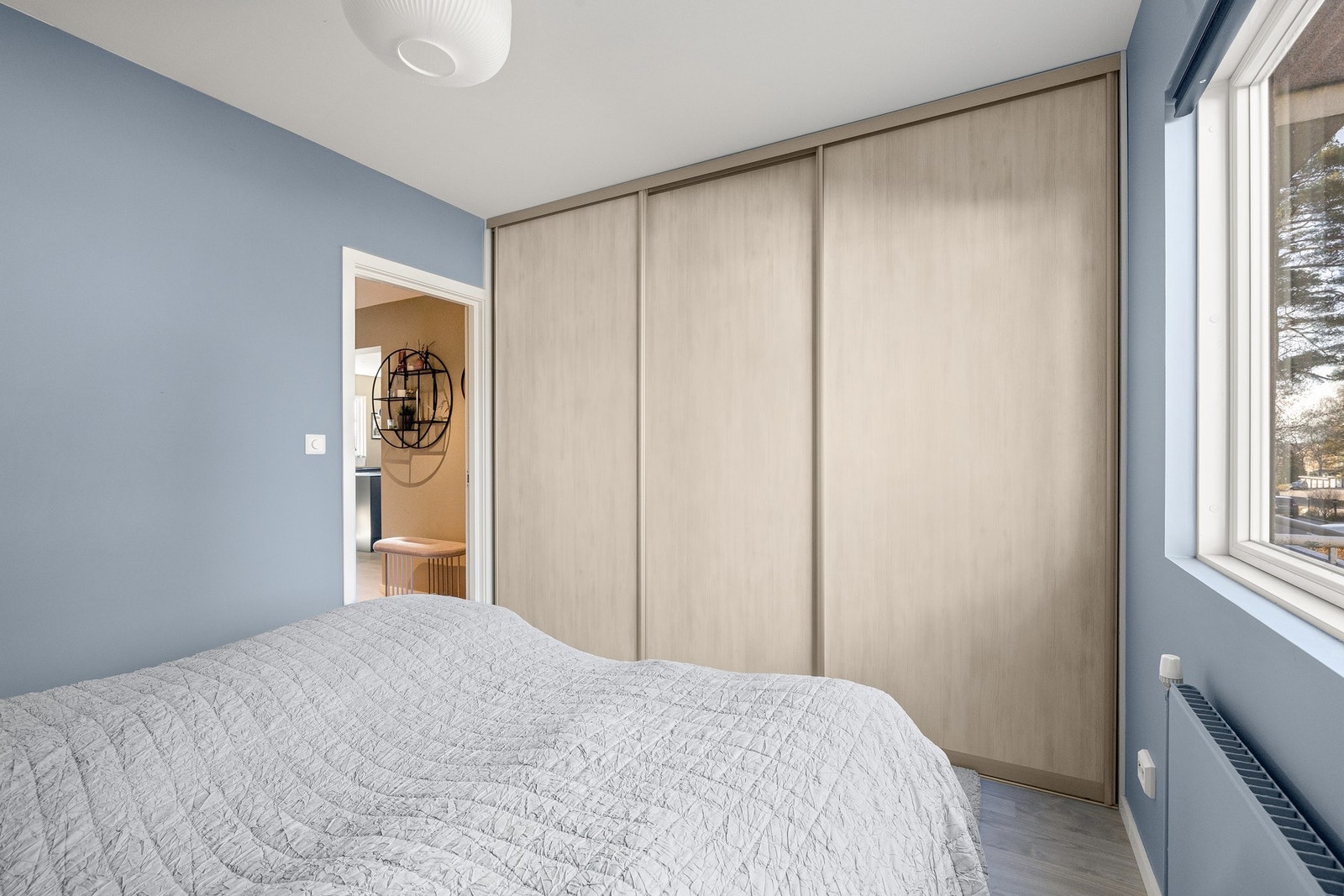 angs den ene veggen er det en romslig skyvedørsgarderobe med to mørke, glatte fronter og en speilfront. Galleribilde