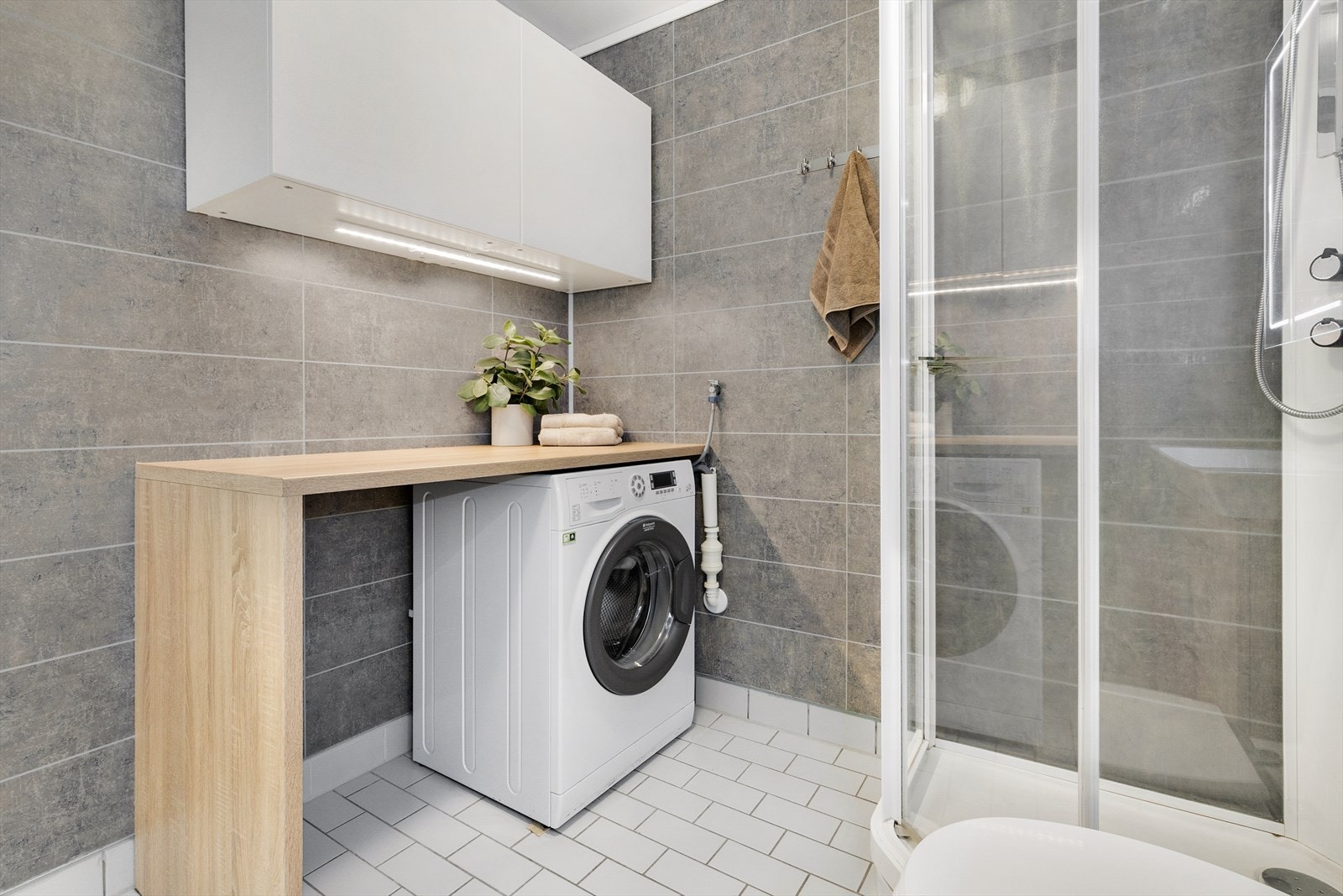 Badet er innredet med dusjkabinett, toalett, heldekkende servant på skuffeseksjon samt speilskap med lys. Opplegg for vaskemaskin og egen benk for oppbevaring og bretting av tøy. Galleribilde