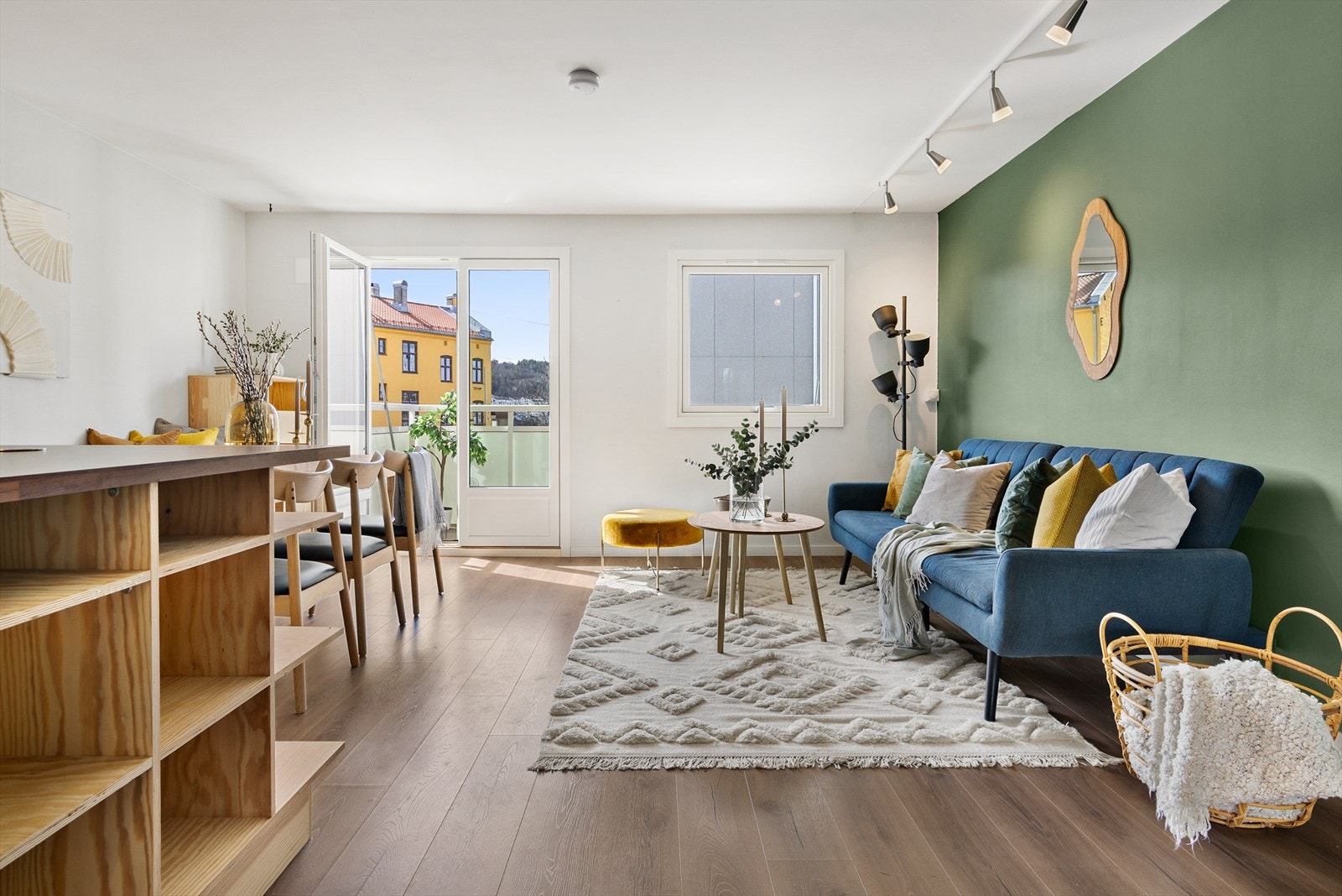 Lysmalt stue med en kontrastvegg i grønt. Galleribilde