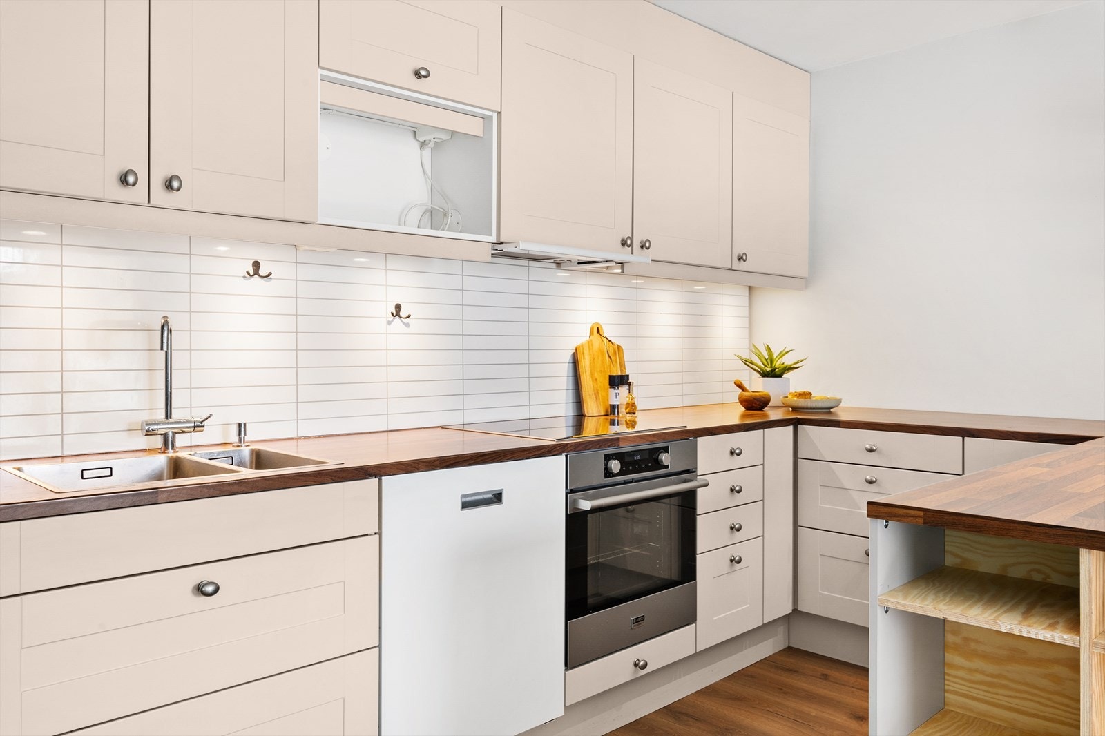 Pent kjøkken med malte, profilerte fronter og benkeplate i laminat. Galleribilde