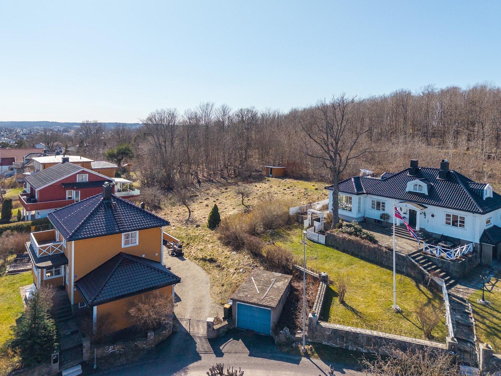 Adkomstveien til tomten er der hvor garasjen med blå dør ligger - denne må rives når man starter byggingen Galleribilde