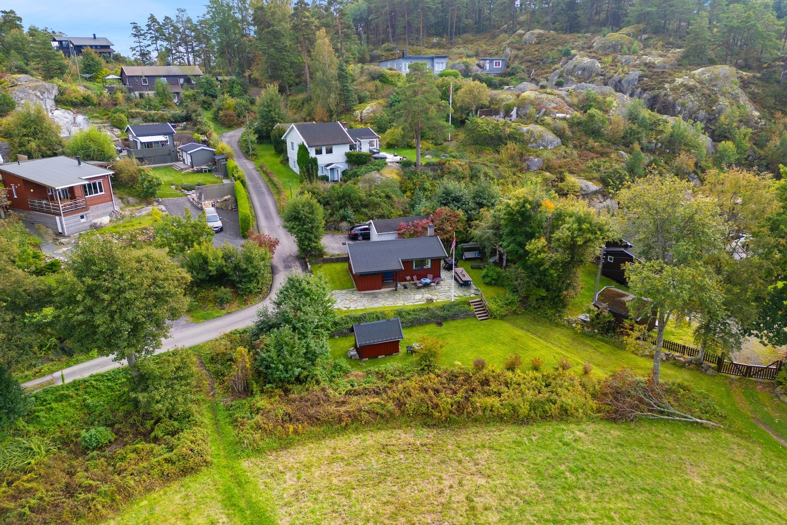 Hytta ligger høyt plassert på tomten, med hageareal og utebod et nivå lavere. Galleribilde