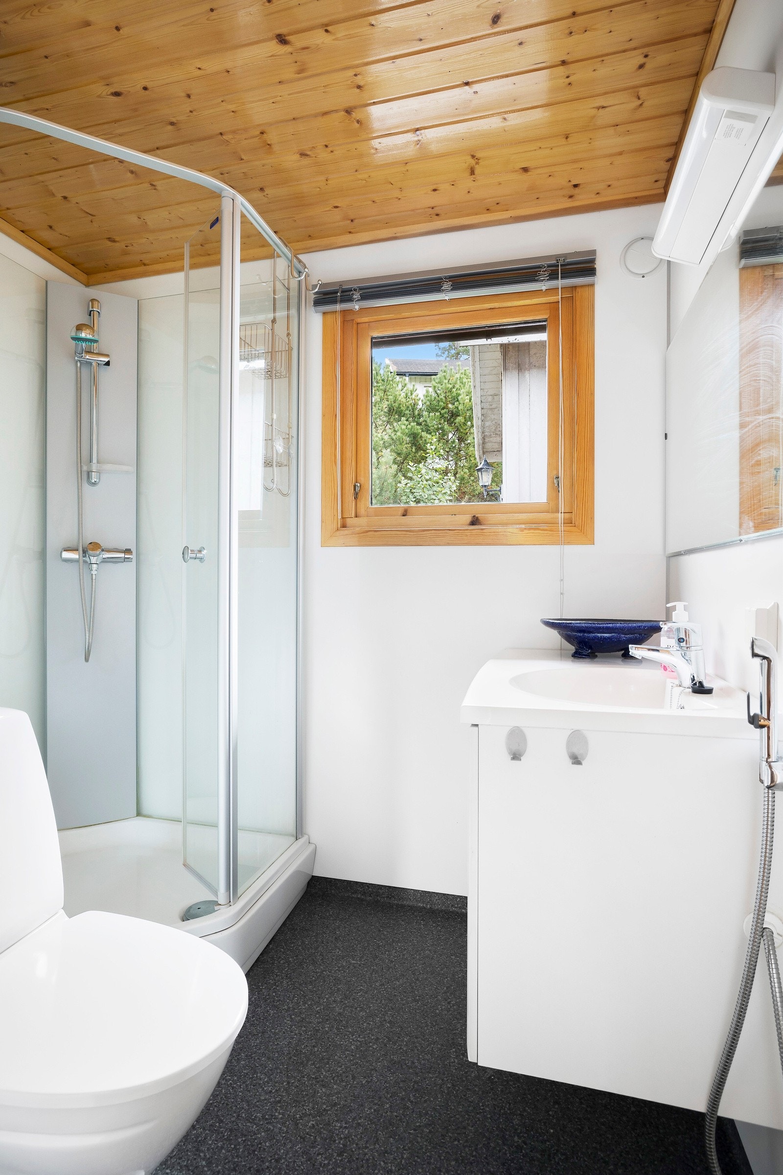 Badet er fra 2007, pent utstyrt med toalett, hvit servantinnredning, dusjkabinett, og en hånddusj på veggen. Galleribilde