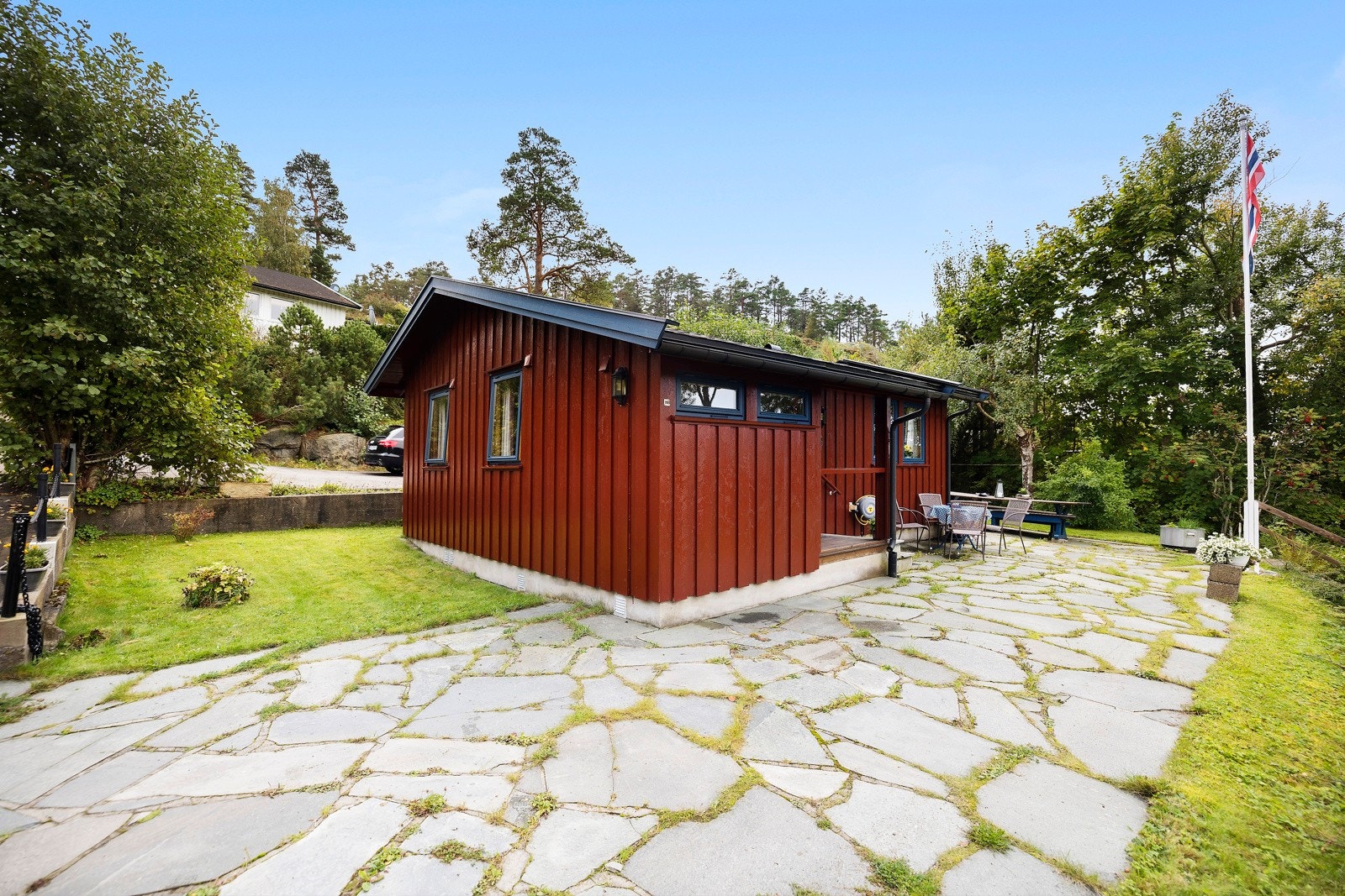 Langs langveggen i nordvest og over langs gavlveggen i sydvest, er det anlagt en skiferkledd uteplass. Galleribilde
