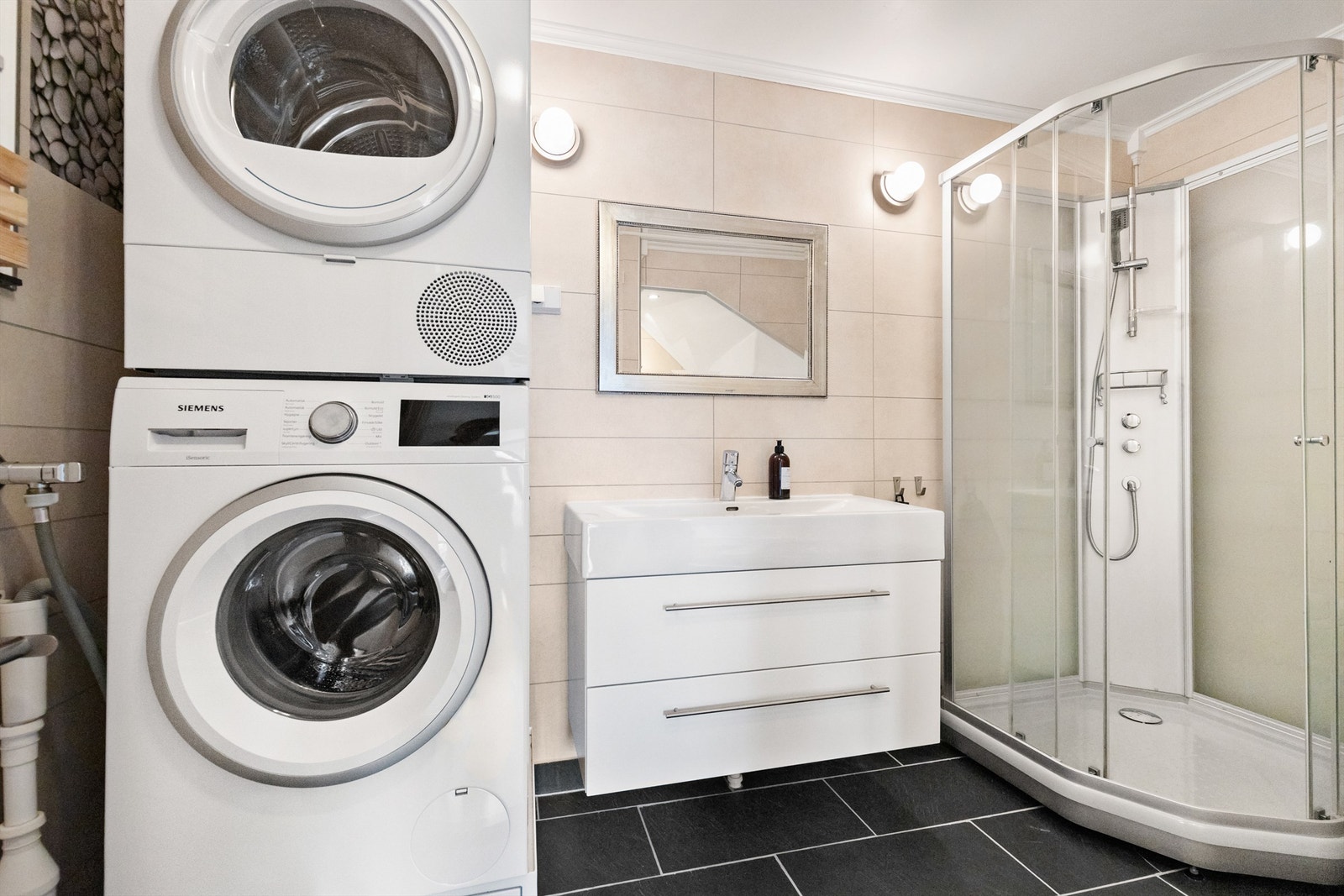 Badet er innredet med vegghengt klosett, servant på innredning, dusjkabinett og badekar. Det er både plass og opplegg for vaskemaskin og tørketrommel. Galleribilde