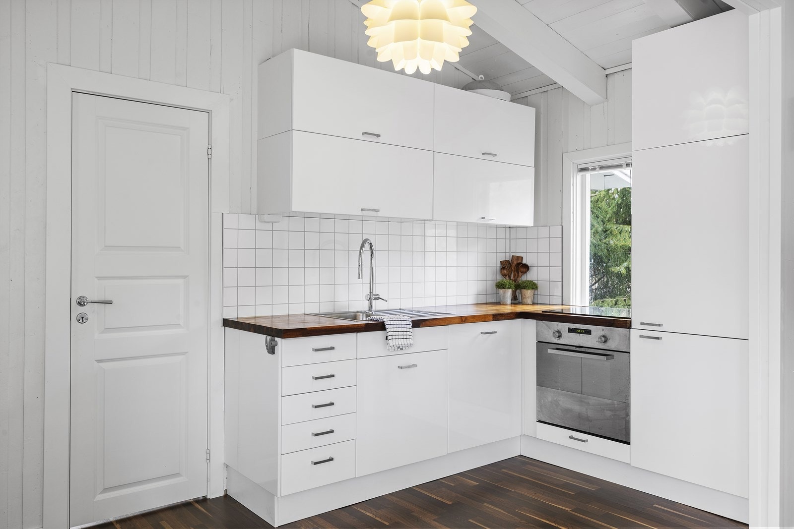 Tidløst kjøkken med hvite, slette fronter og heltre benkeplate Galleribilde