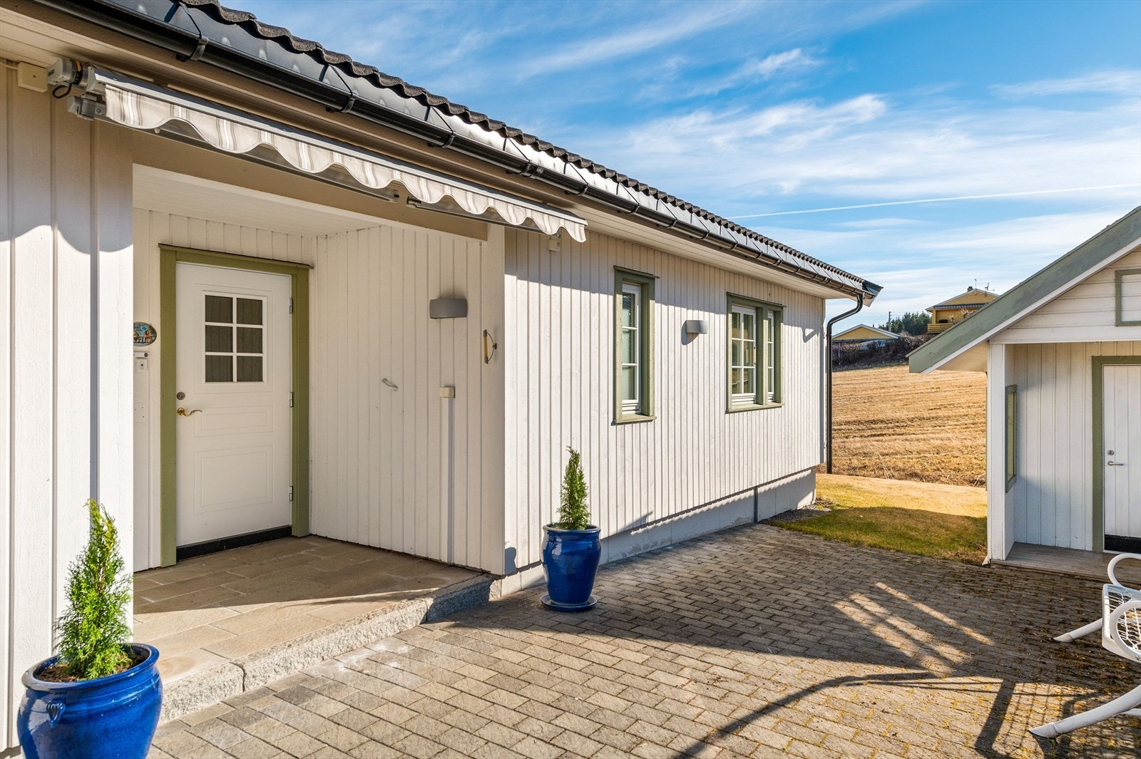 Inngangsparti våningshus hvor uteareal er pent opparbeidet med beleggningsstein. Galleribilde