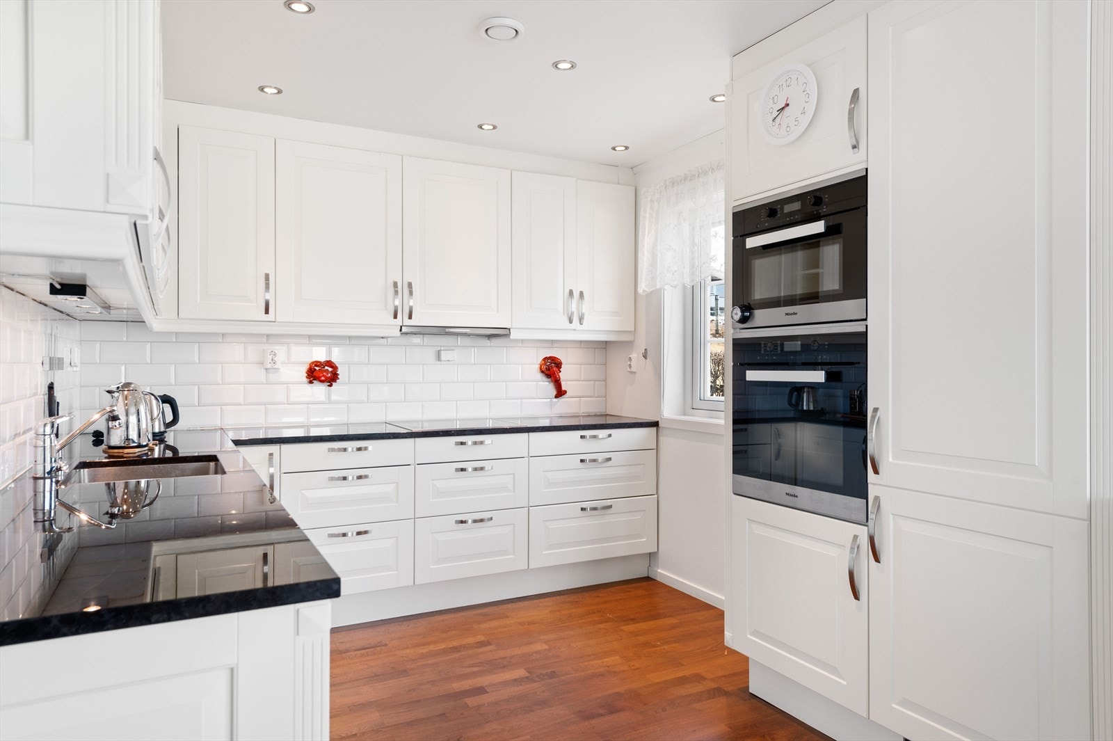 Anvendelig kjøkken med integrerte hvitevarer, mye skap og benkeplass Galleribilde