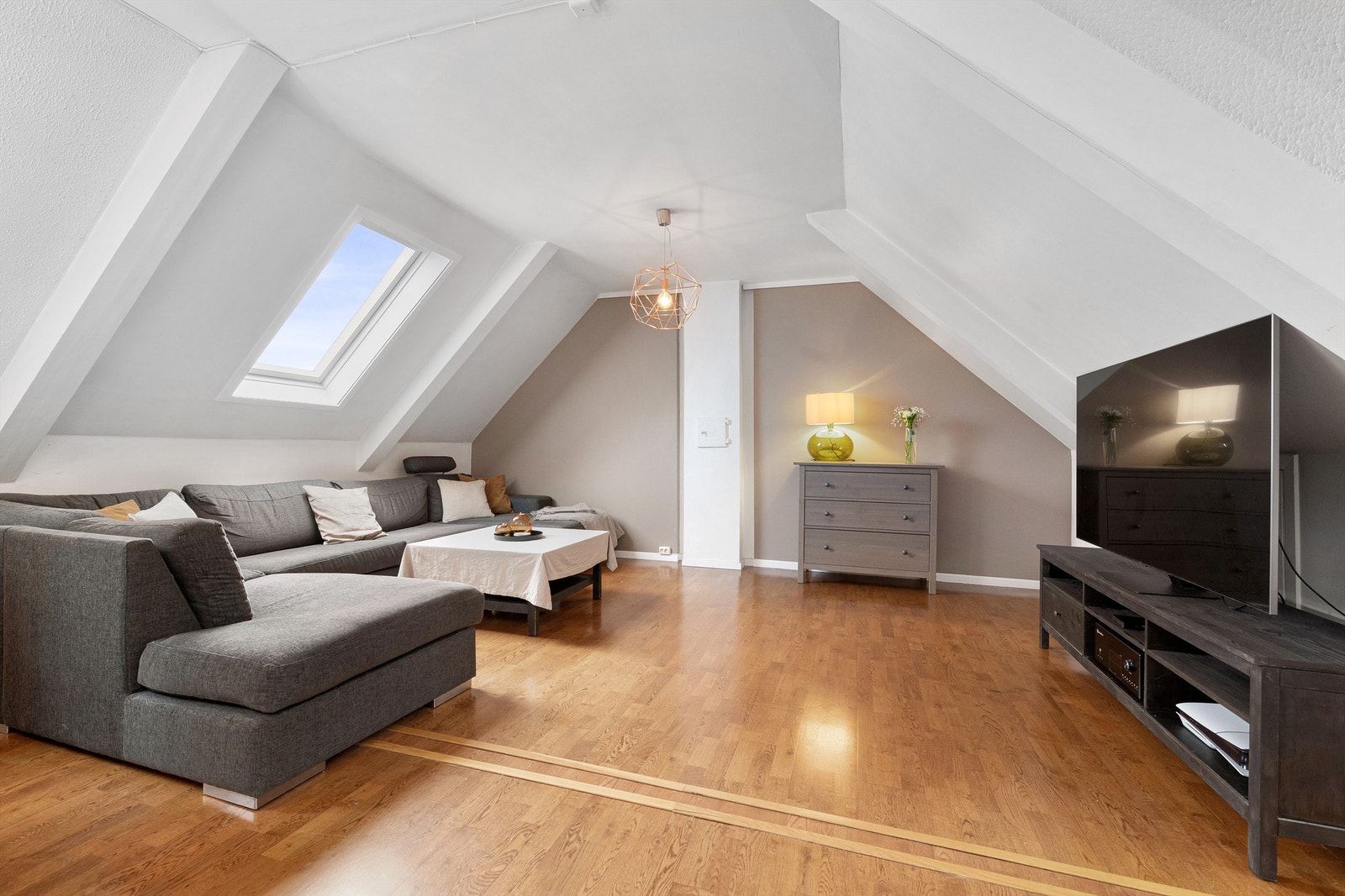 Leiligheten har skråtak og takvinduer noe som gir en særpreg - her fra sofakroken på stuen Galleribilde