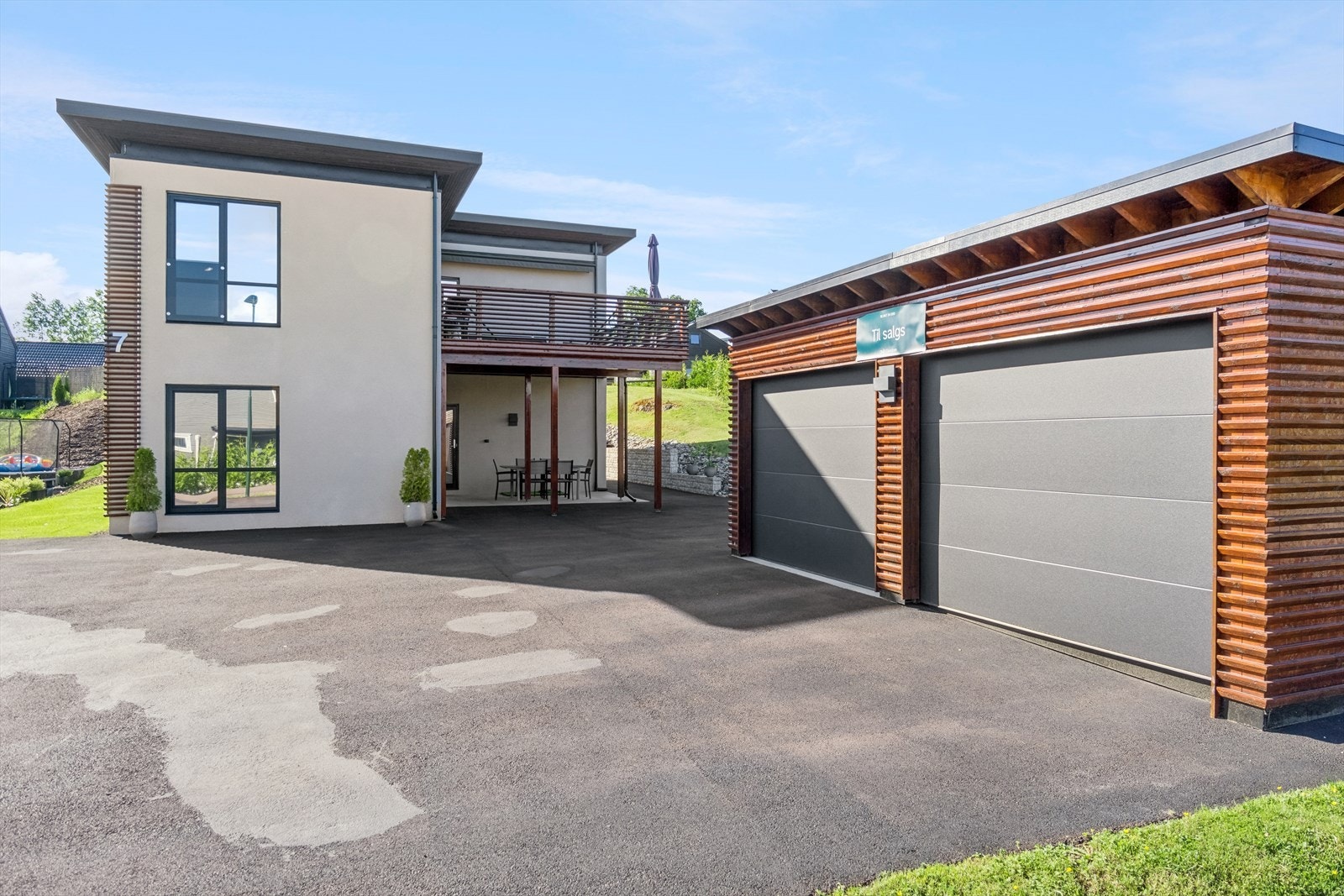 Romslig dobbelgarasje fra 2022 bygget i husets stil og materialvalg med elbil-lader og bod i bakkant. Galleribilde