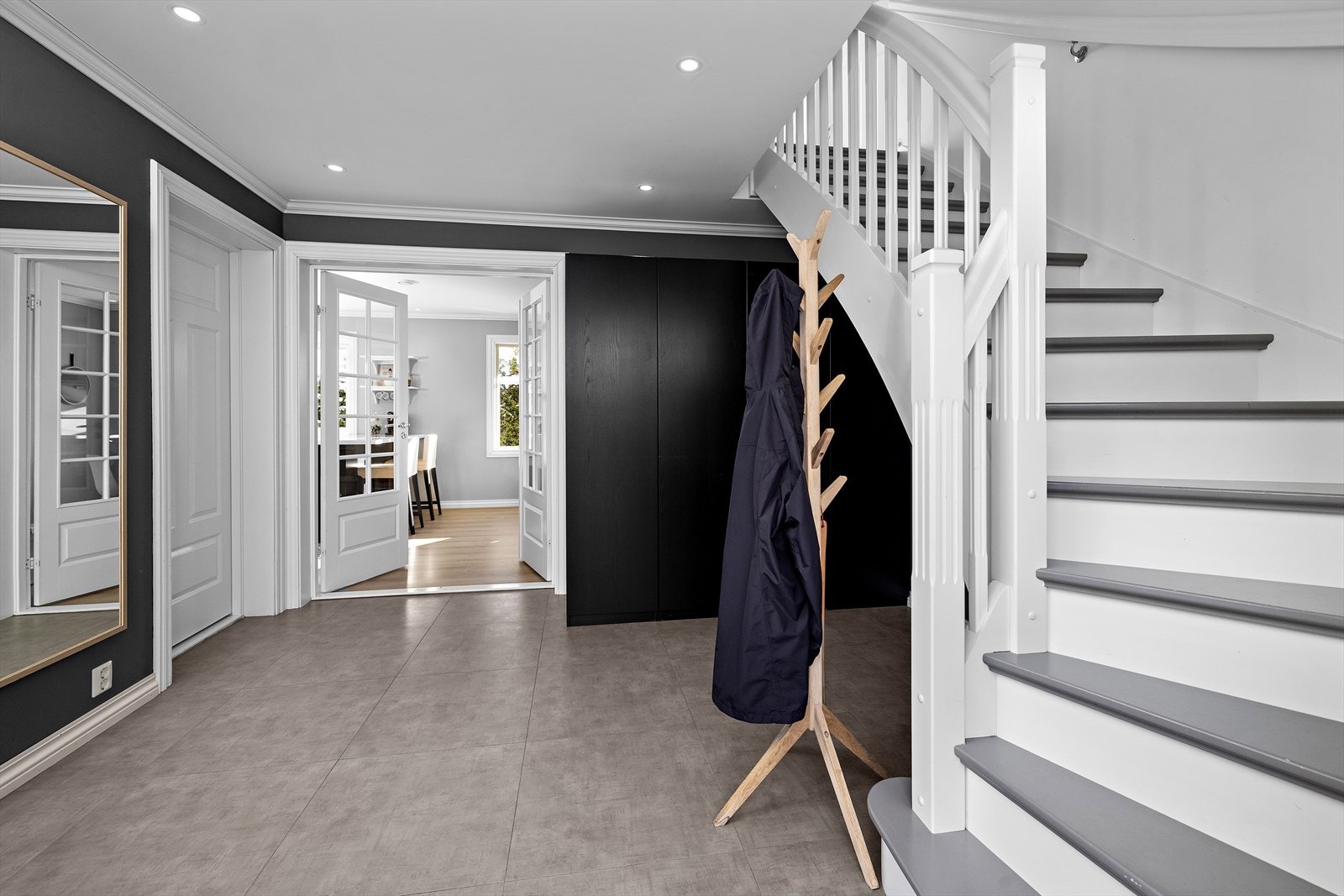 Lys og romslig flislagt hall med downlights i tak hvor det også er god plass til å henge ifra seg yttertøyet i garaderobeløsning under trappen og til å sette ifra seg sko, noe som gjør det enkelt å holde orden i inngangspartiet. Galleribilde