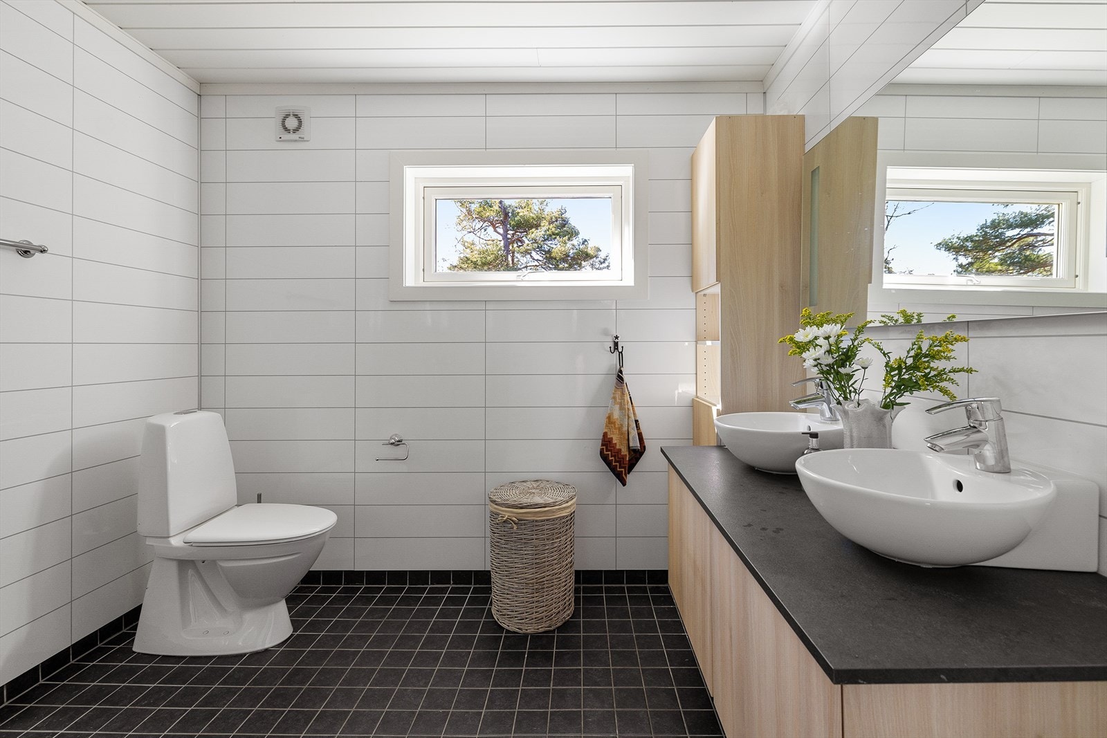 Badet har flislagt gulv med varmekabler under og våtromsplater på veggene _ sort og hvit. Galleribilde