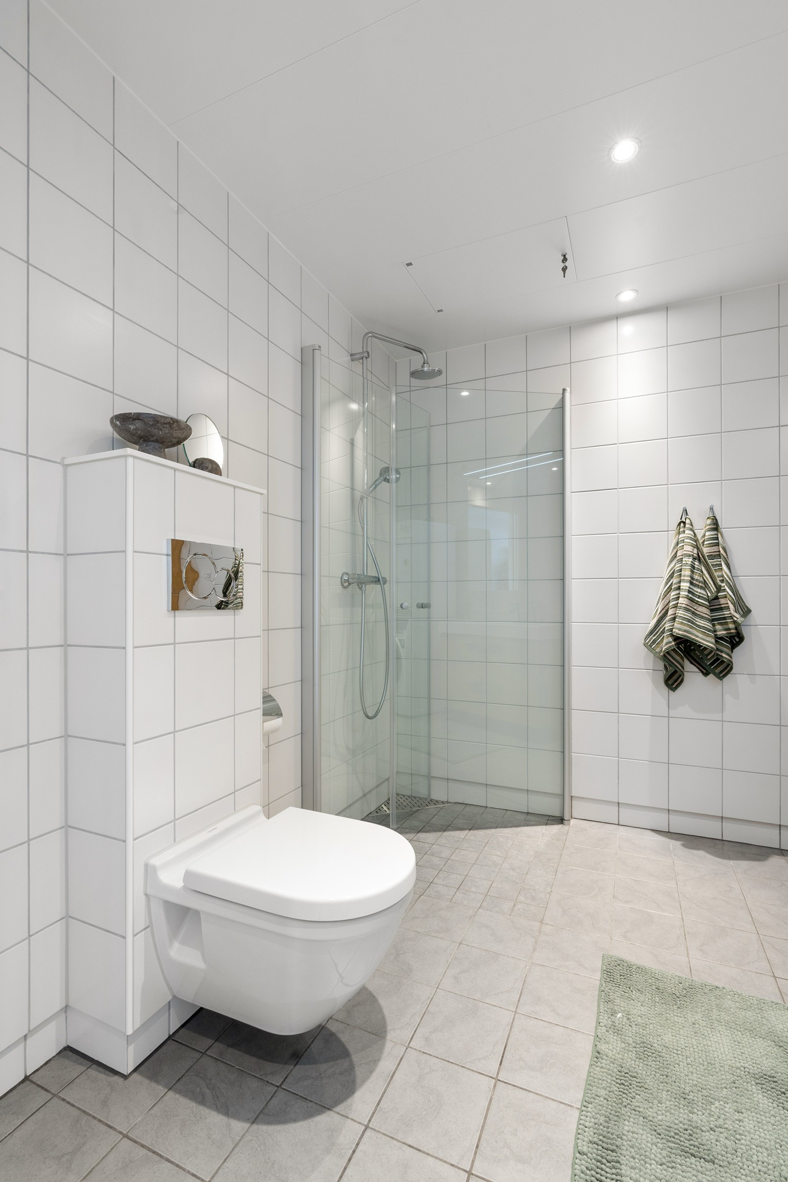 Badet er romslig og har plass til både dusjkabinett og oppbevaring.