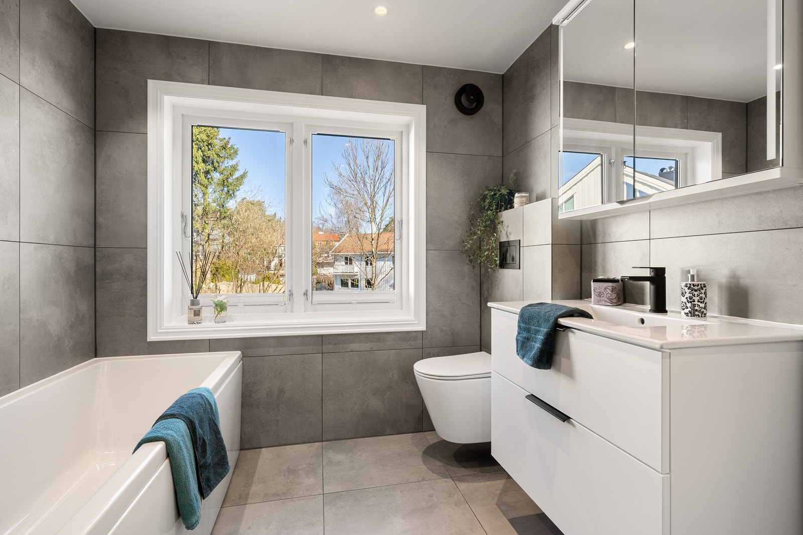 Badet er funksjonelt og elegant med flislagte overflater, varmekabler og appstyrt ventilasjon. Galleribilde