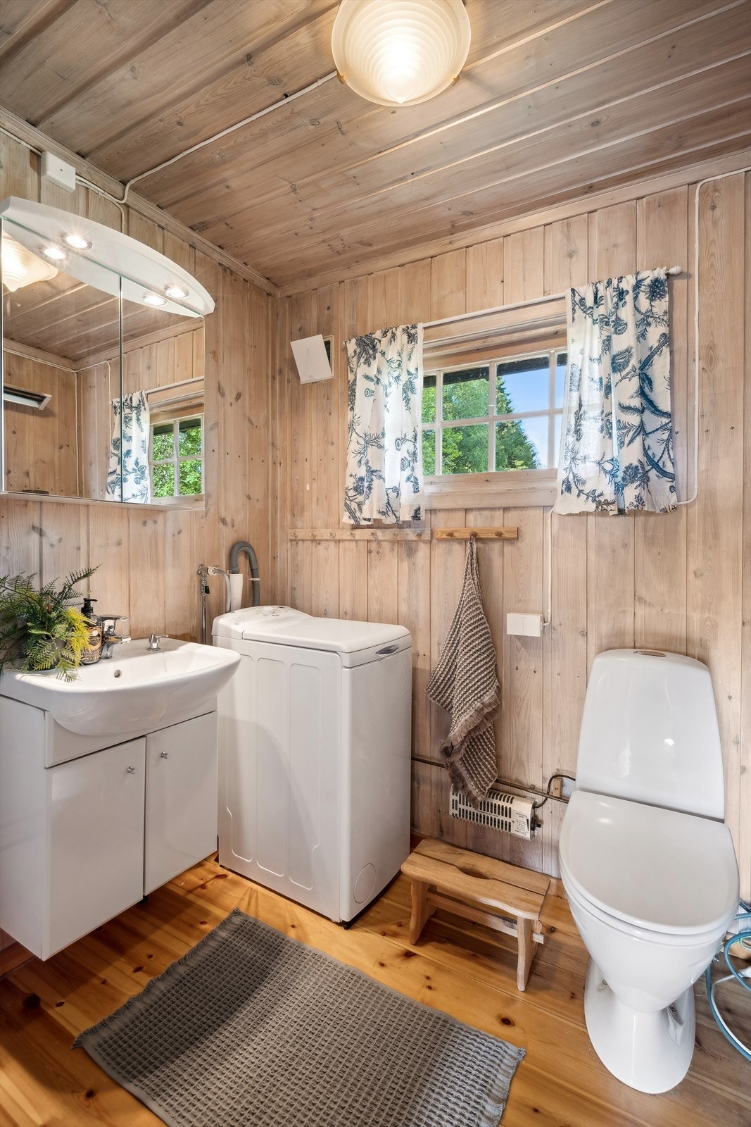 Badet har panel på vegger og tregulv. Rommet har ikke membran og det er montert enkel baderomsinnredning med hvite glatte fronter og vask i porselen med ett-grepsarmatur. Galleribilde
